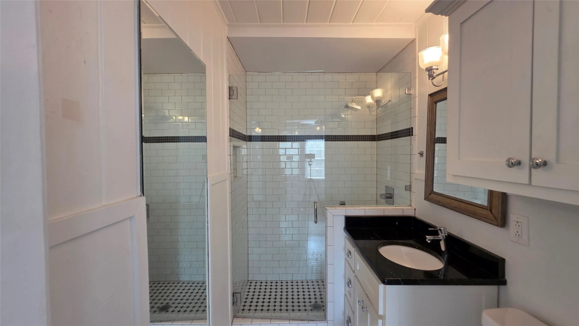 Ensuite bath is complete with built-in storage, ample lighting, and a glass shower door.