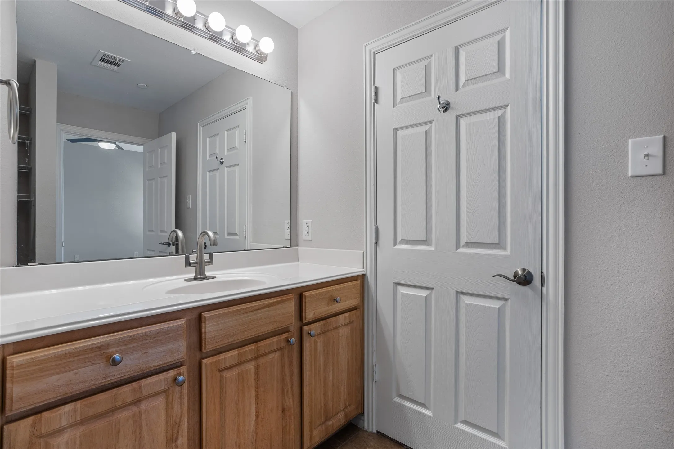 Vanity with wood-finish cabinetry, integrated sink, and brushed nickel faucet