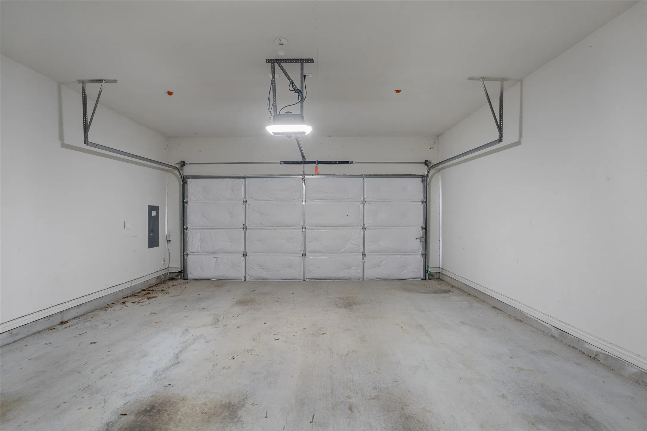 Garage with concrete flooring, white walls, and an overhead garage door opener