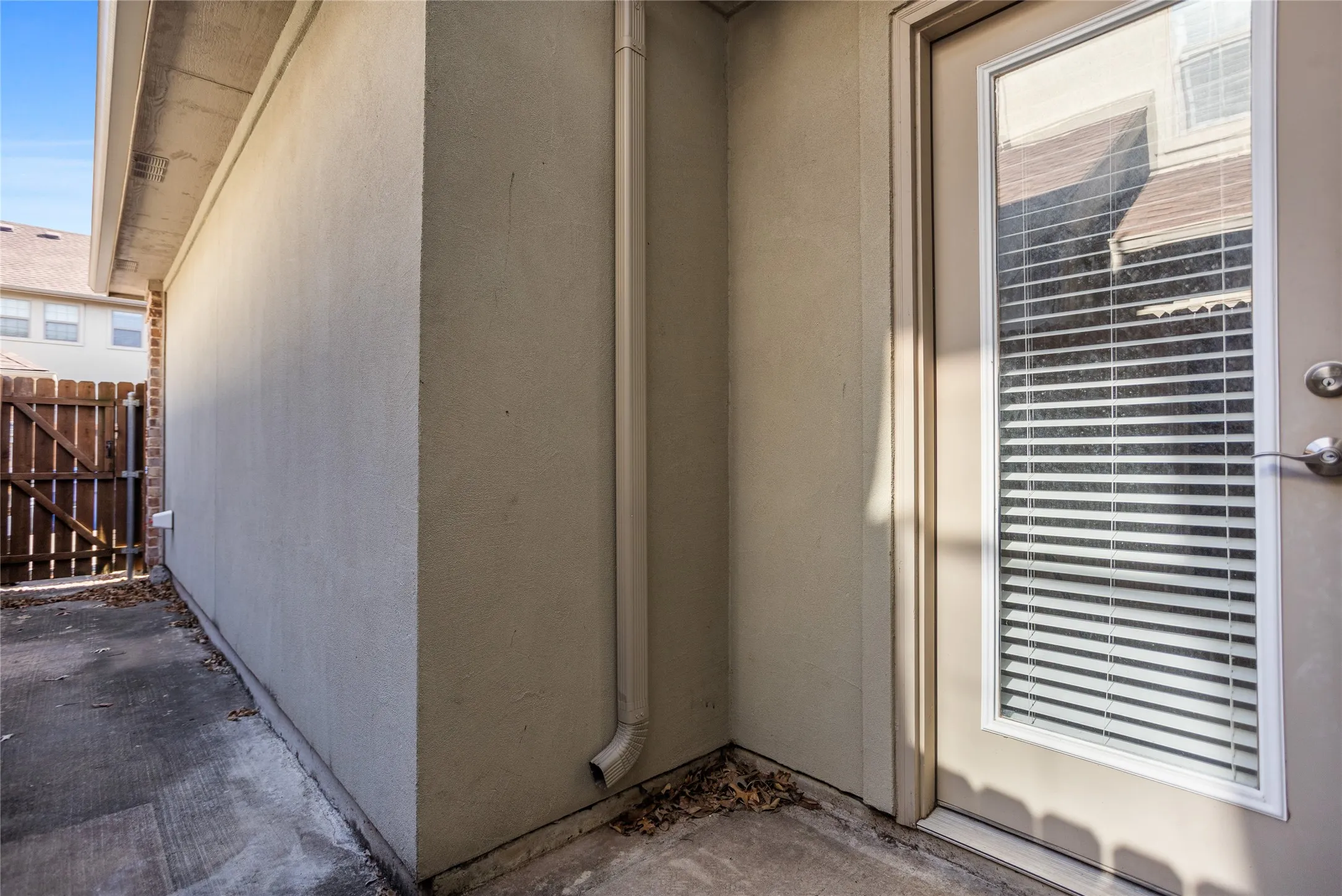 Stucco exterior with a rear entry door featuring integrated blinds
