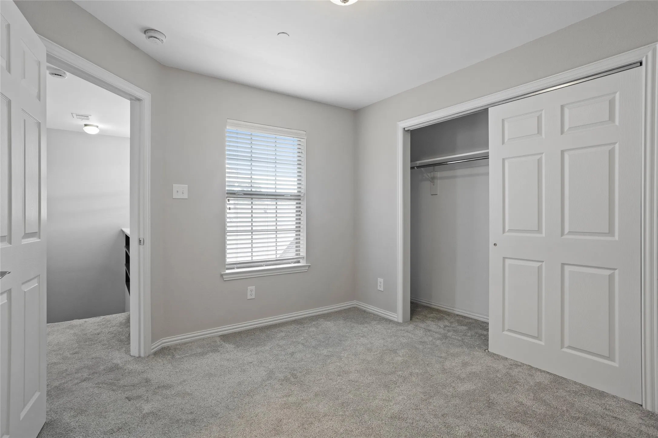 Carpeted flooring, window with blinds, sliding closet doors, and recessed lighting