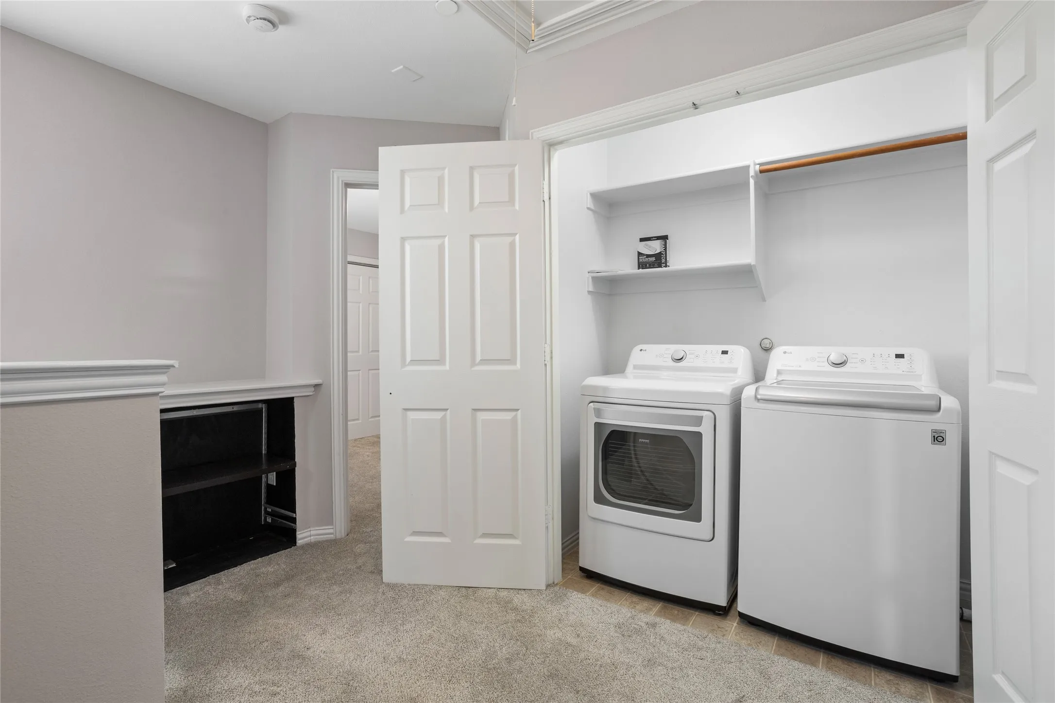 Laundry closet featuring a washer and dryer, built-in shelving, and a hanging rod