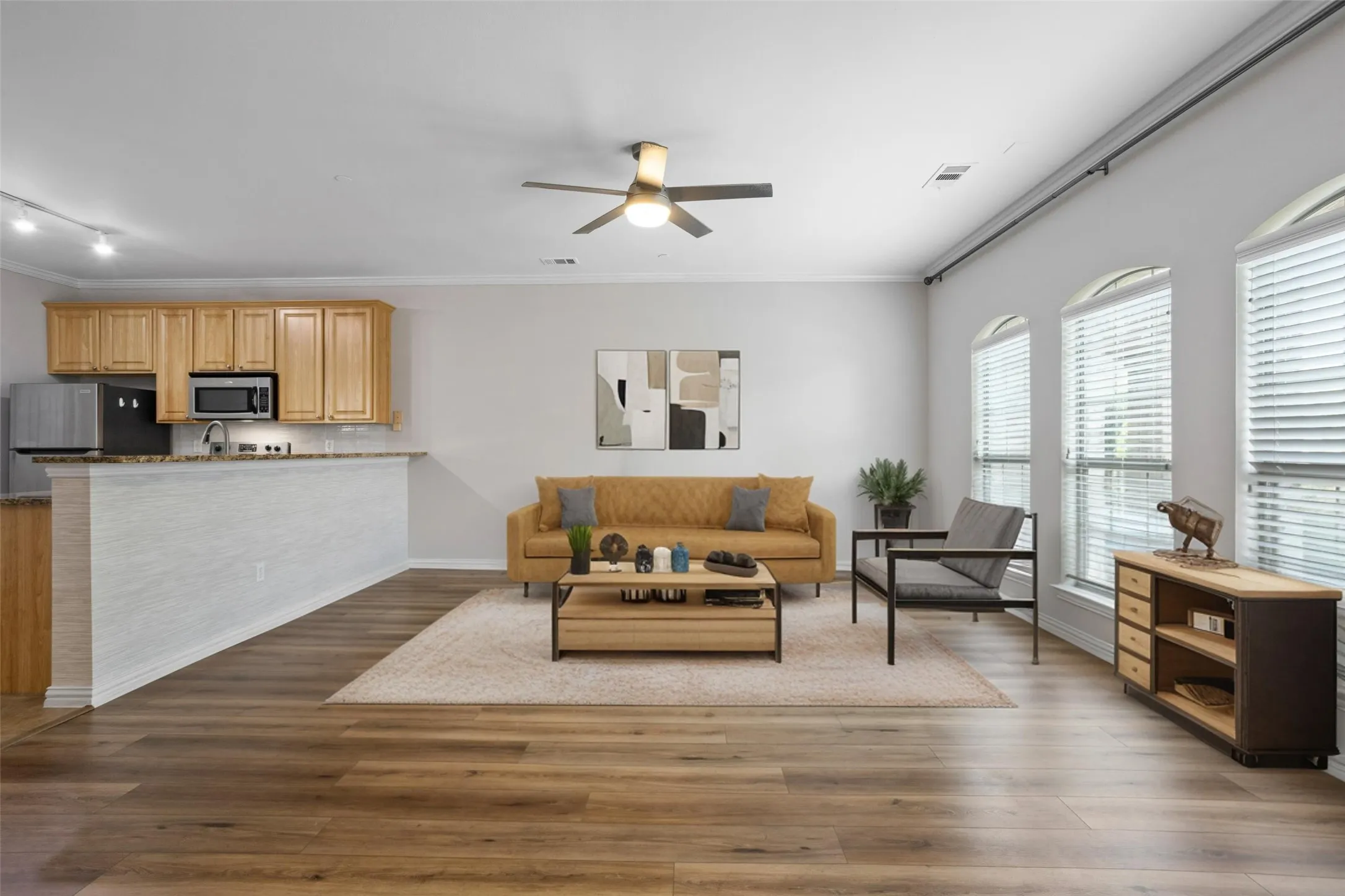 Open-concept living space with wood-finish flooring, vaulted ceilings, and arched windows