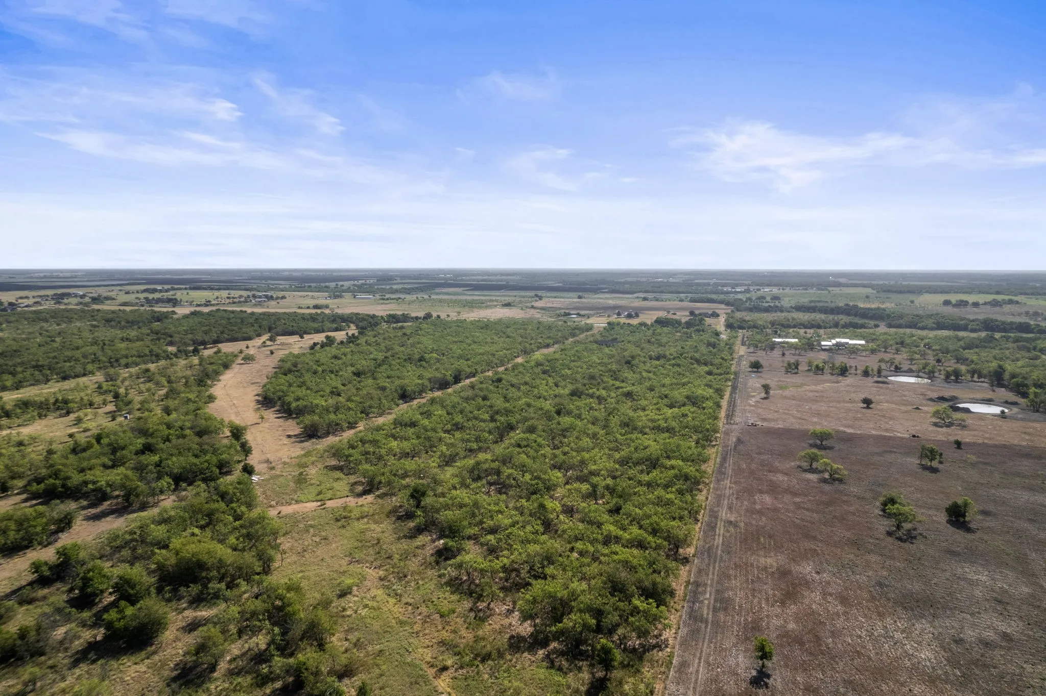 Expansive land featuring wooded areas and open fields