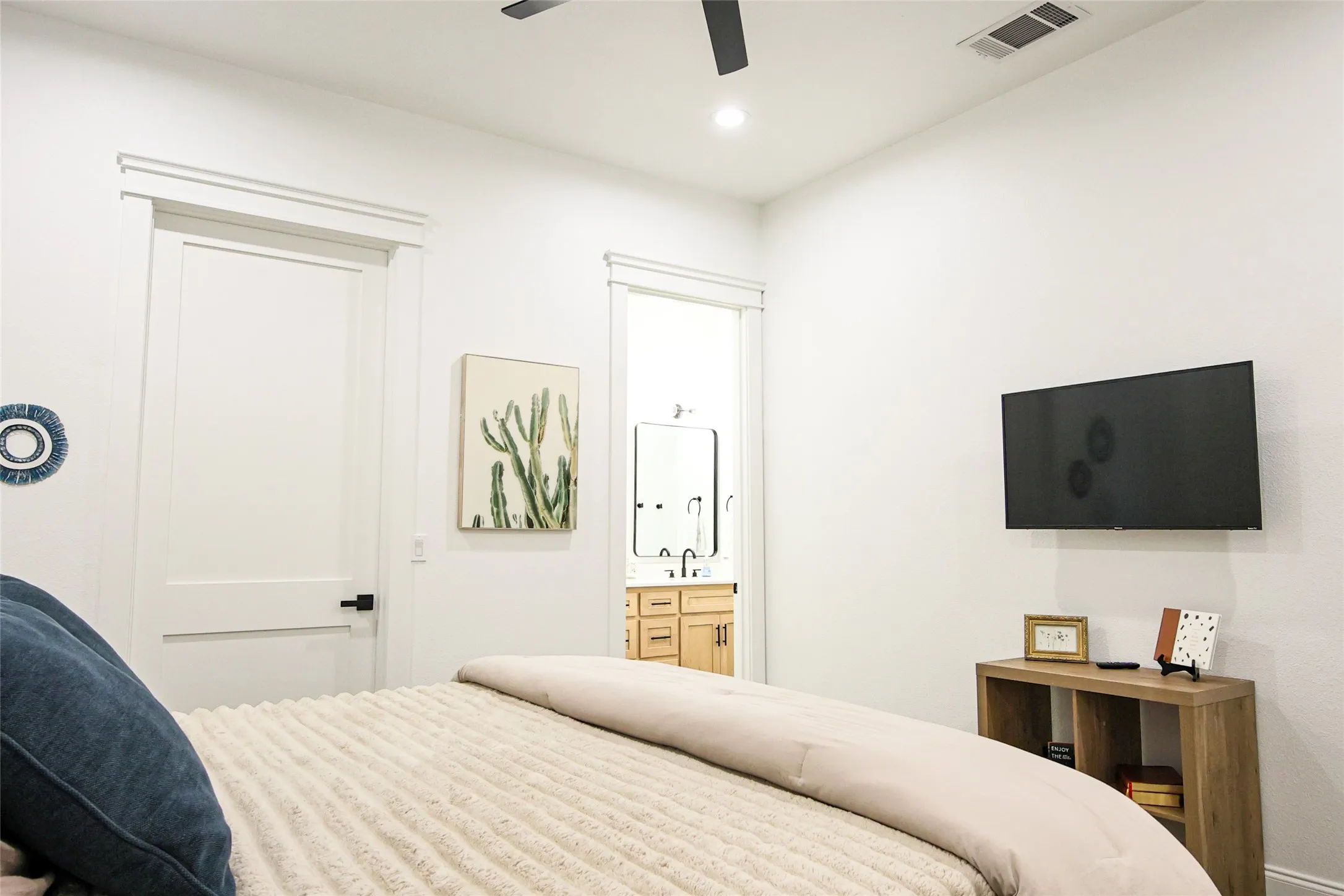 White interior walls, modern ceiling fan, recessed lighting, flat panel interior doors with matte black hardware, and an en-suite bathroom with a vanity and mirror