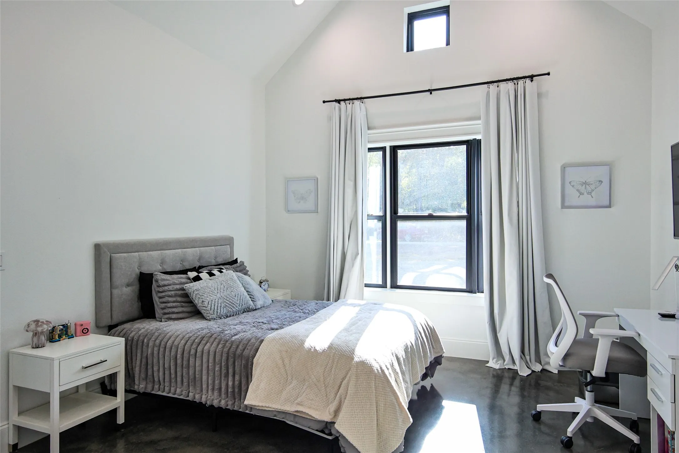 Vaulted ceiling with an upper transom window, black-framed windows, and concrete flooring