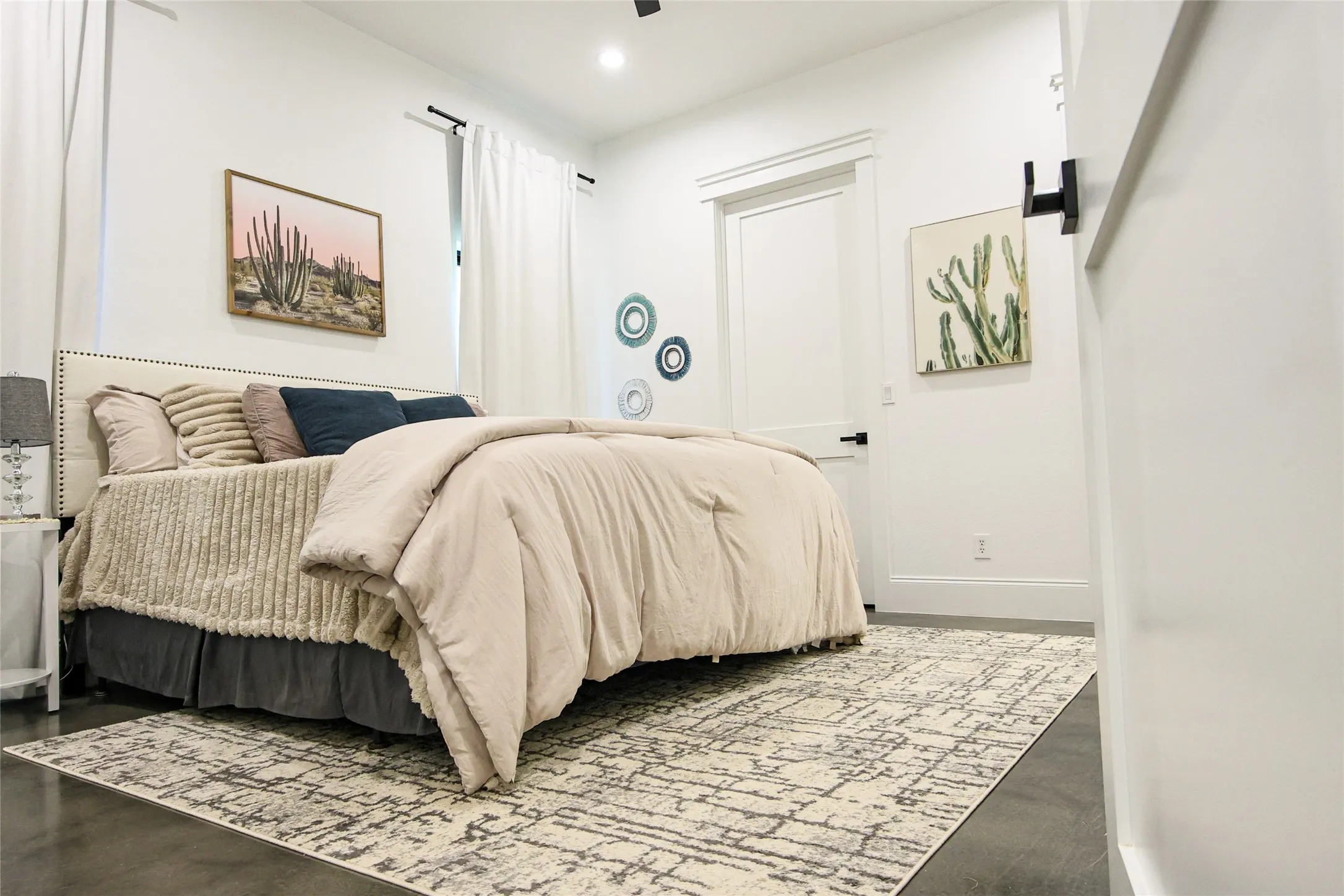 Recessed lighting, dark flooring, crisp white walls, and a white interior door with black hardware