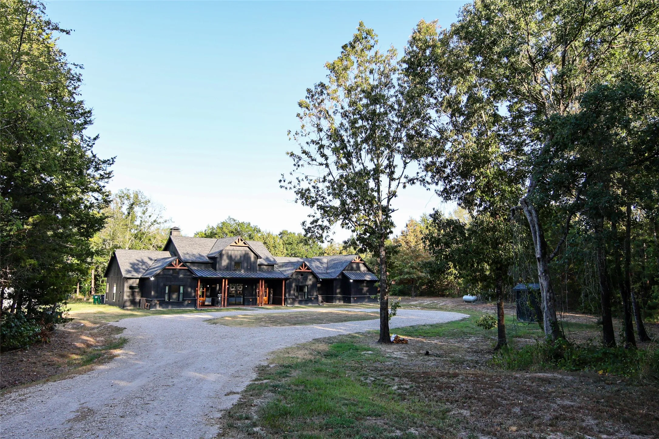 Wood-sided exterior with a prominent front entrance, multiple gables, and a gravel driveway
