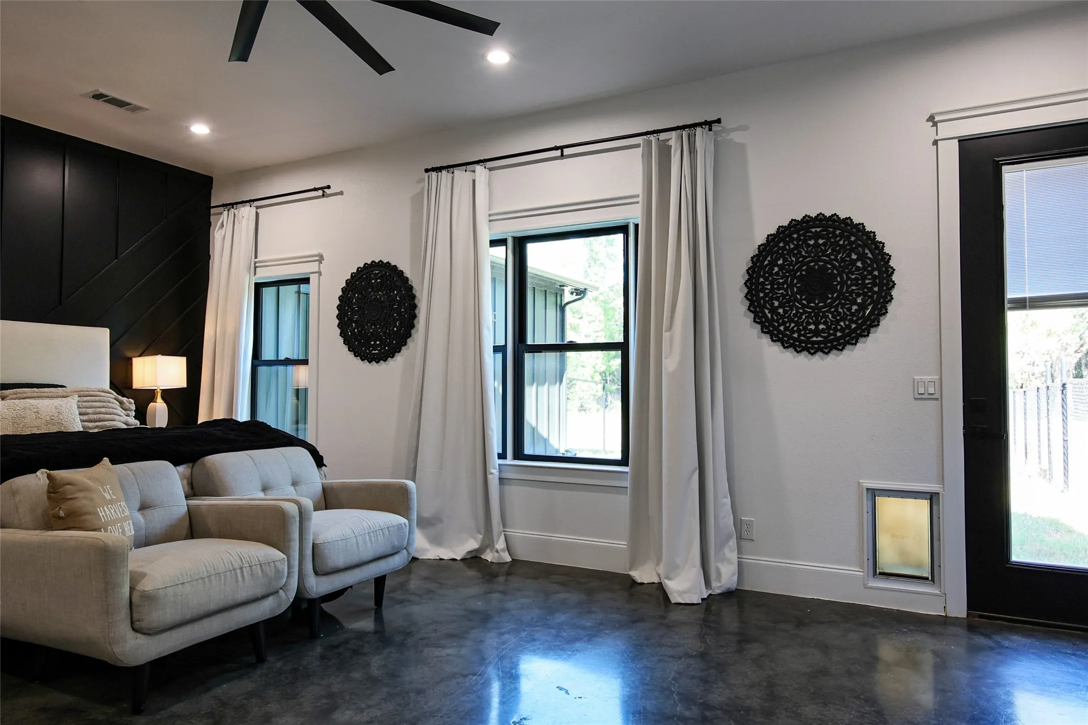 Polished concrete flooring, recessed lighting, ceiling fan, and a black accent wall with applied molding