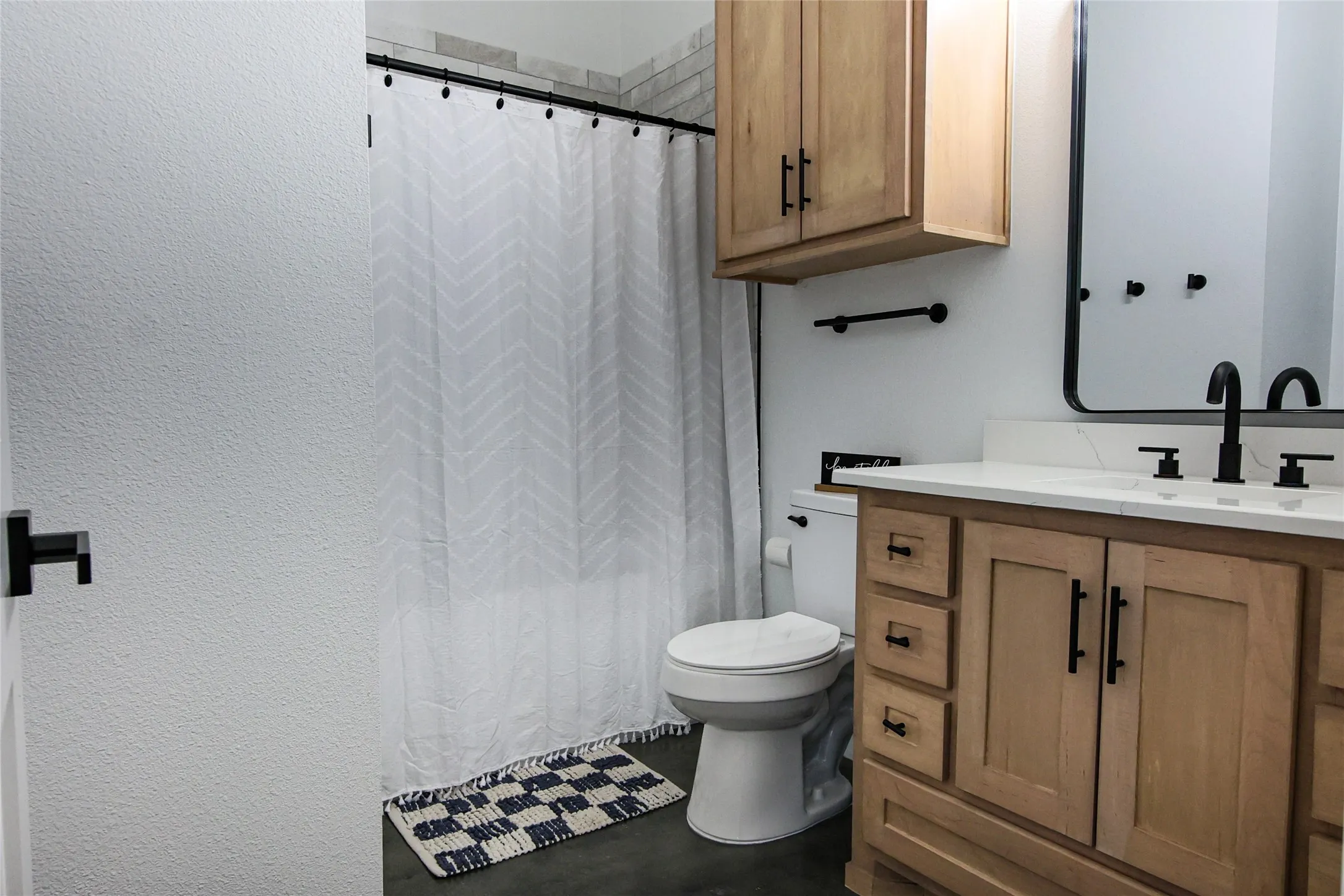 Light wood-tone vanity with a white countertop and matte black fixtures