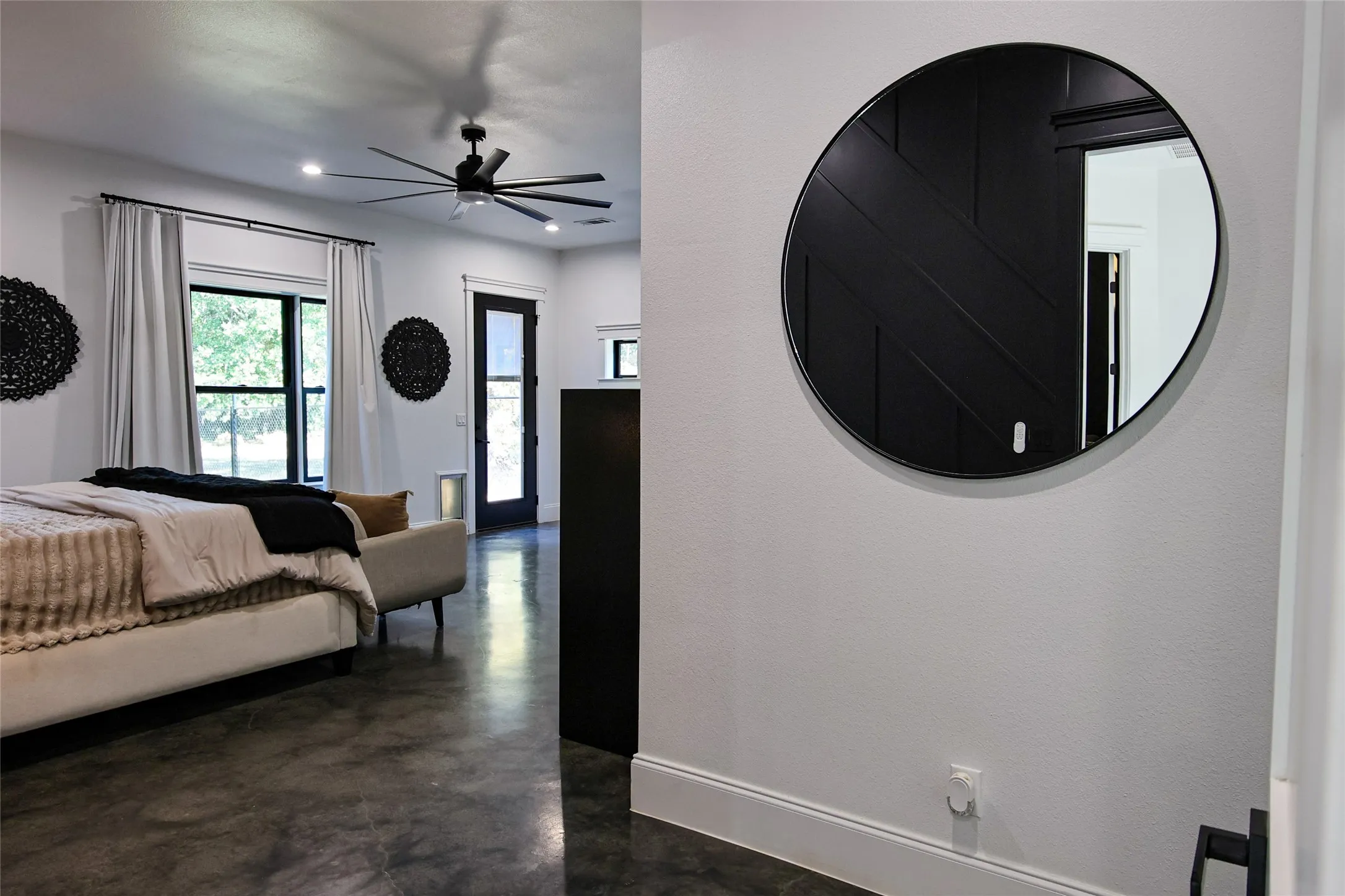 Polished concrete flooring, large window with dark trim, recessed lighting, and a dark-bladed ceiling fan