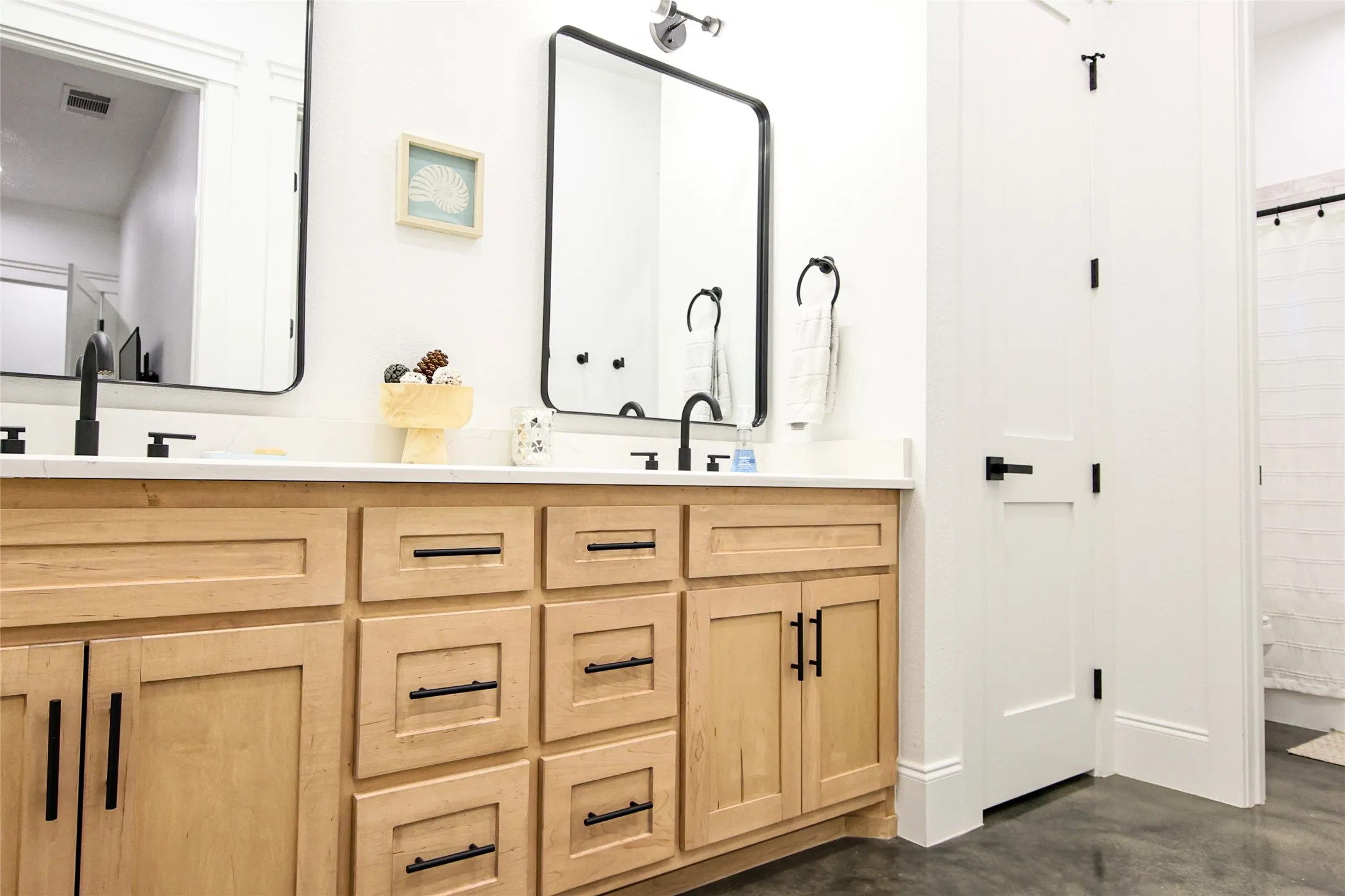 Dual wood-finish vanities with white countertops, matte black faucets, and rectangular mirrors
