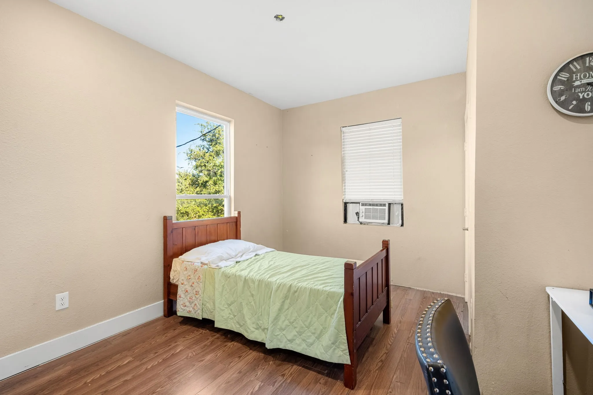 Wood-finish flooring with light-toned walls, featuring a window and a window-mounted air conditioning unit