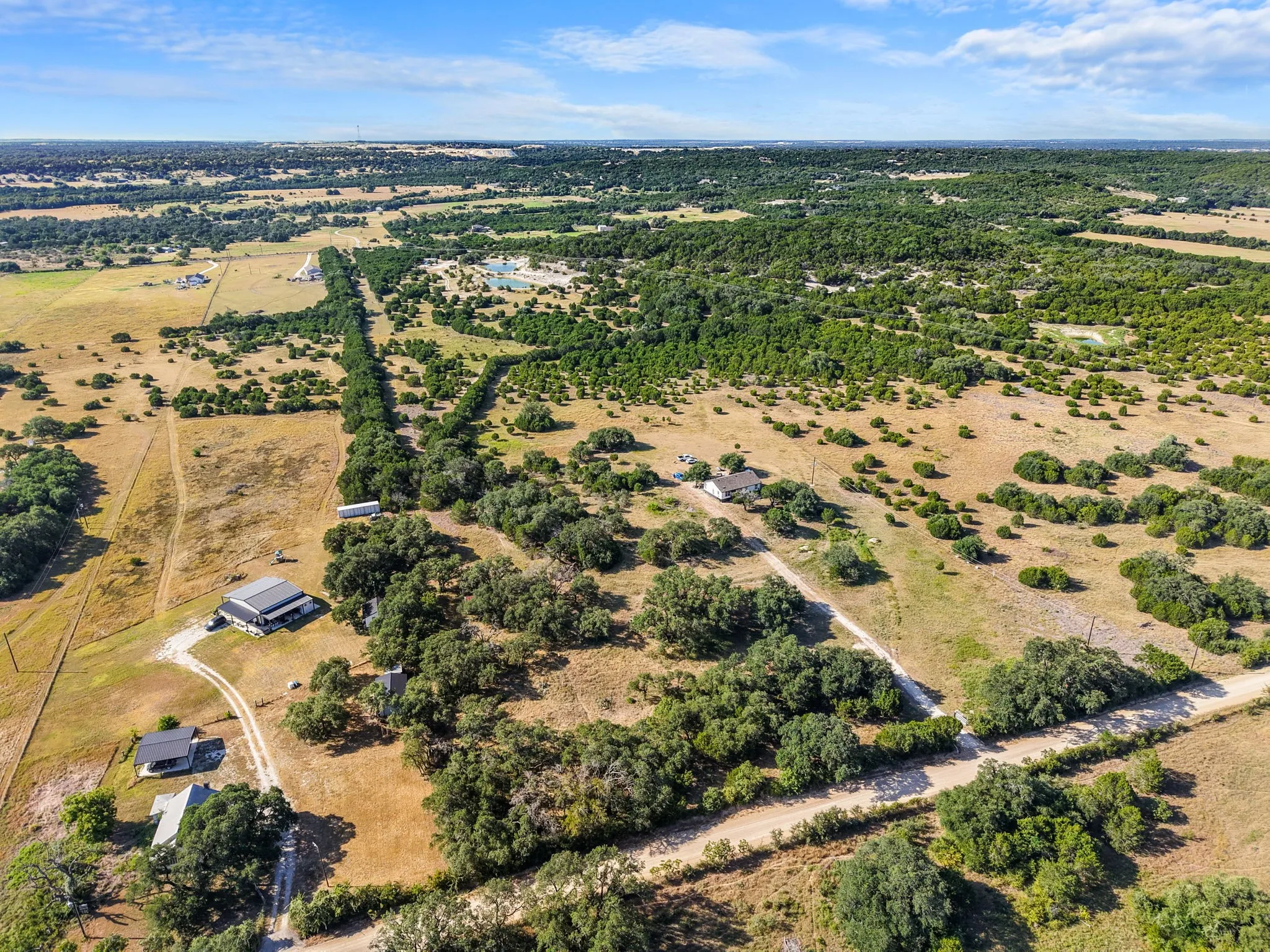 Expansive acreage featuring multiple structures, mature trees, and natural landscaping