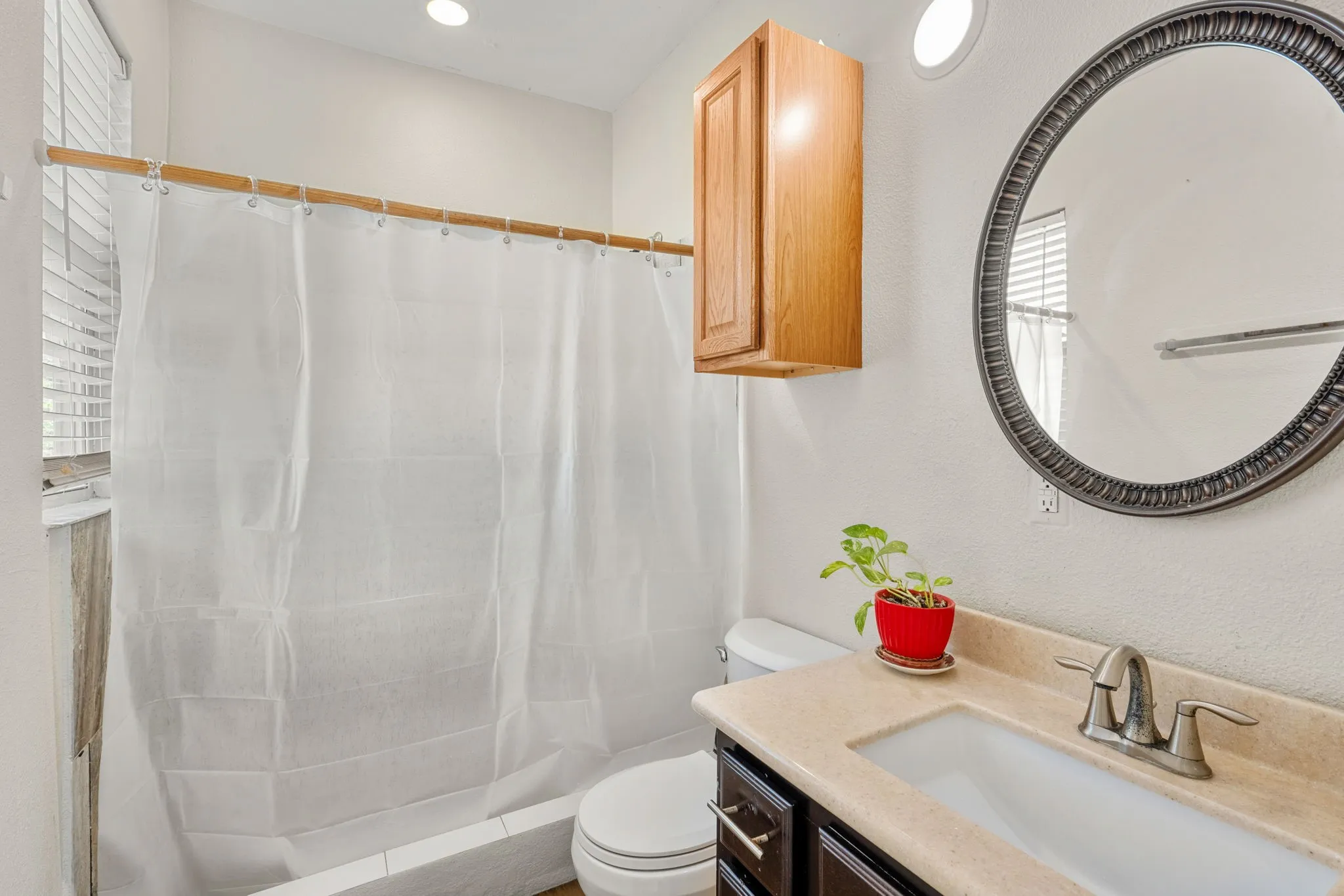 Bathroom with a built-in vanity featuring a single basin sink and a round framed mirror