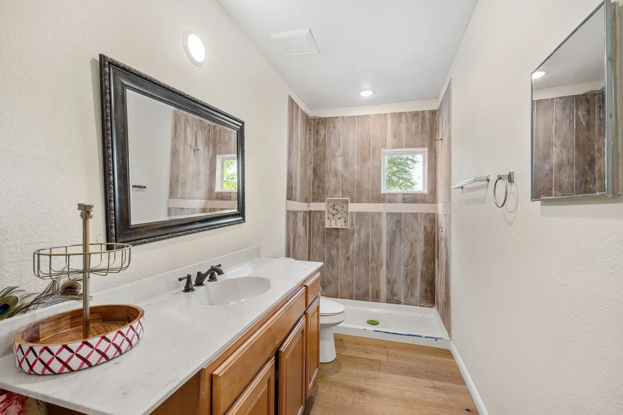 Bathroom featuring a wood-finish floor, wood vanity with a white countertop, and a shower with wood-finish tile walls