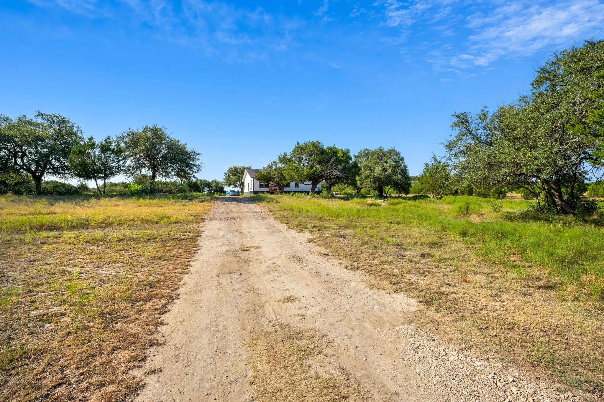 Expansive gravel pathway leading to a white-sided residence
