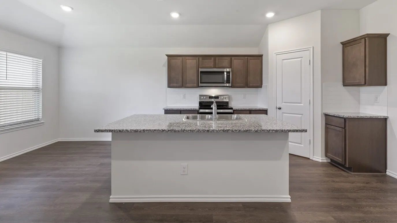Kitchen island with a double basin sink, stainless steel appliances, dark wood-finish cabinetry, and wood-finish flooring