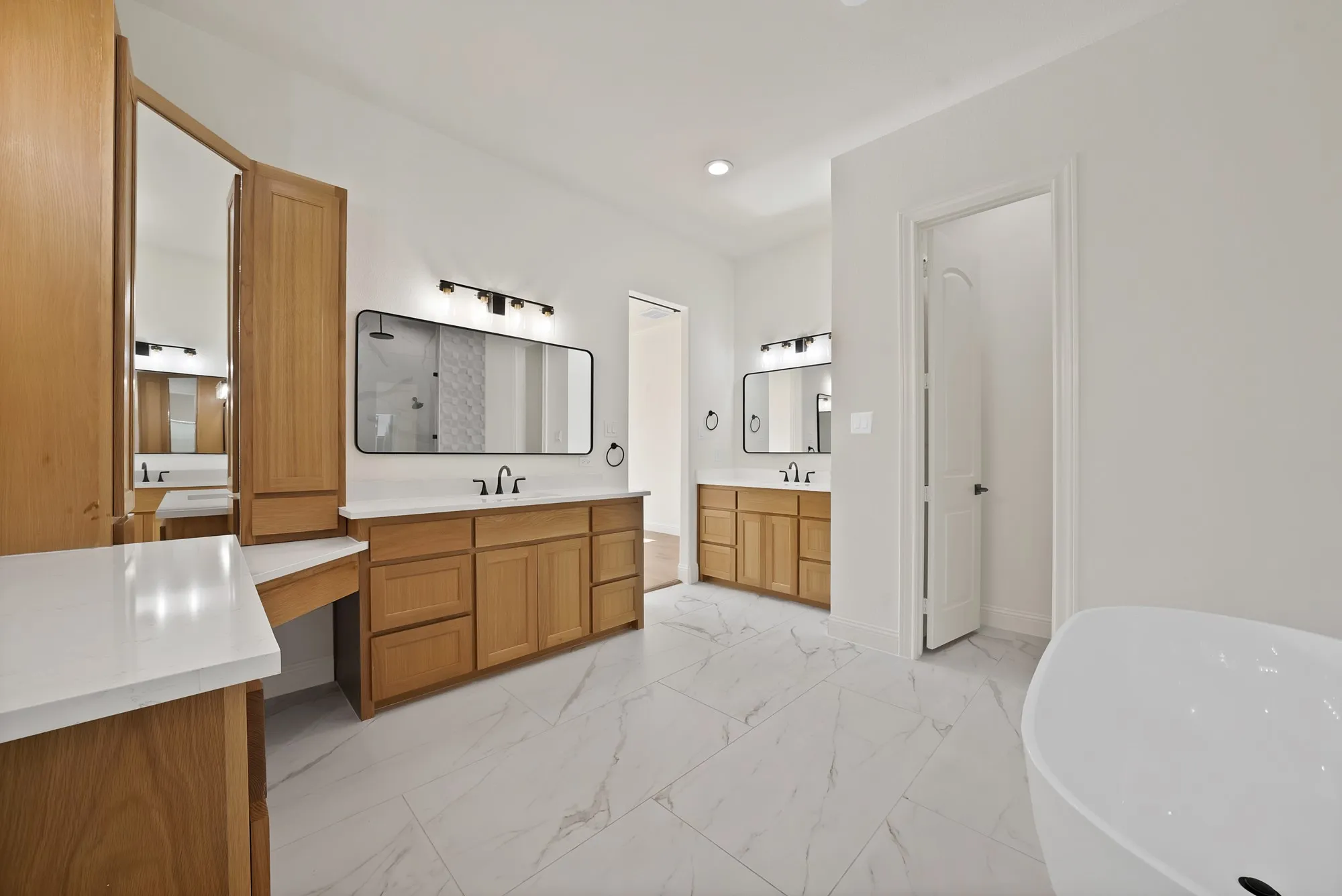 Dual vanities with white countertops, light wood-finish cabinetry, and contemporary black-framed mirrors