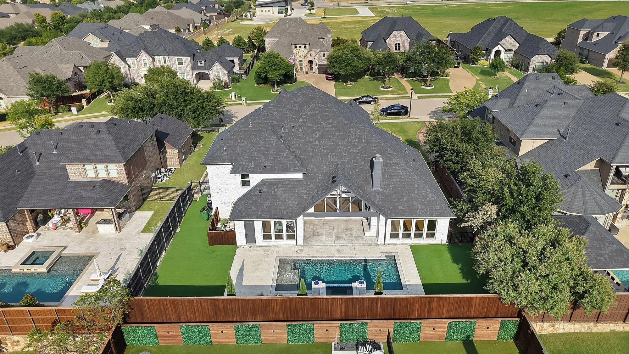 Spacious backyard featuring a rectangular swimming pool, integrated spa, artificial turf lawn, and extensive patio area