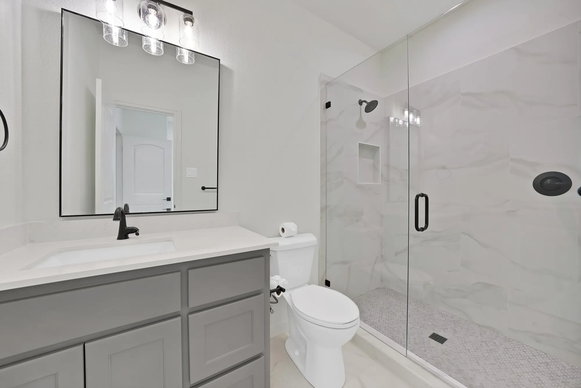 Full glass shower enclosure with a rainfall shower head and a built-in shower niche