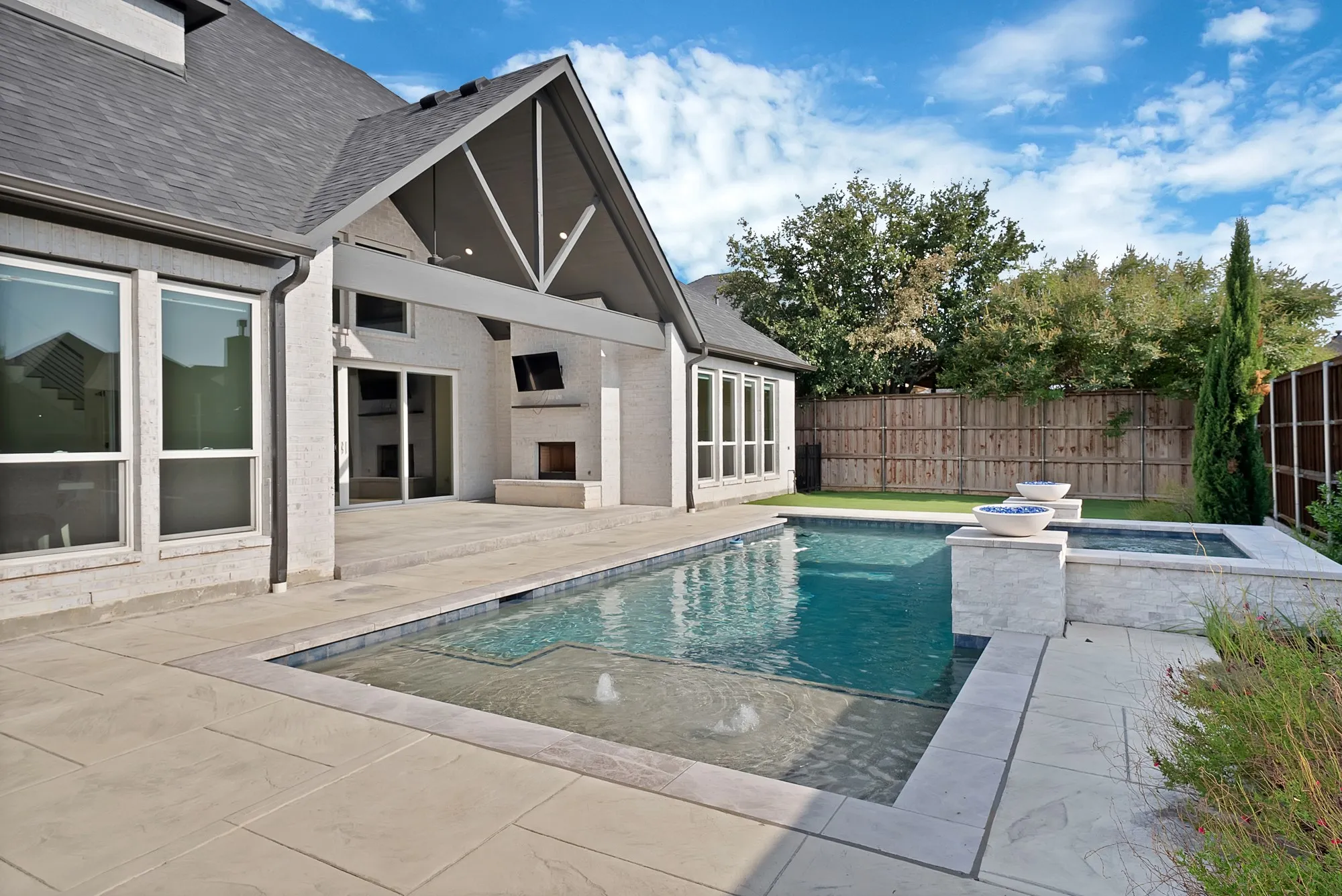 Exterior featuring a swimming pool, integrated spa, covered patio, outdoor fireplace, and sliding glass doors