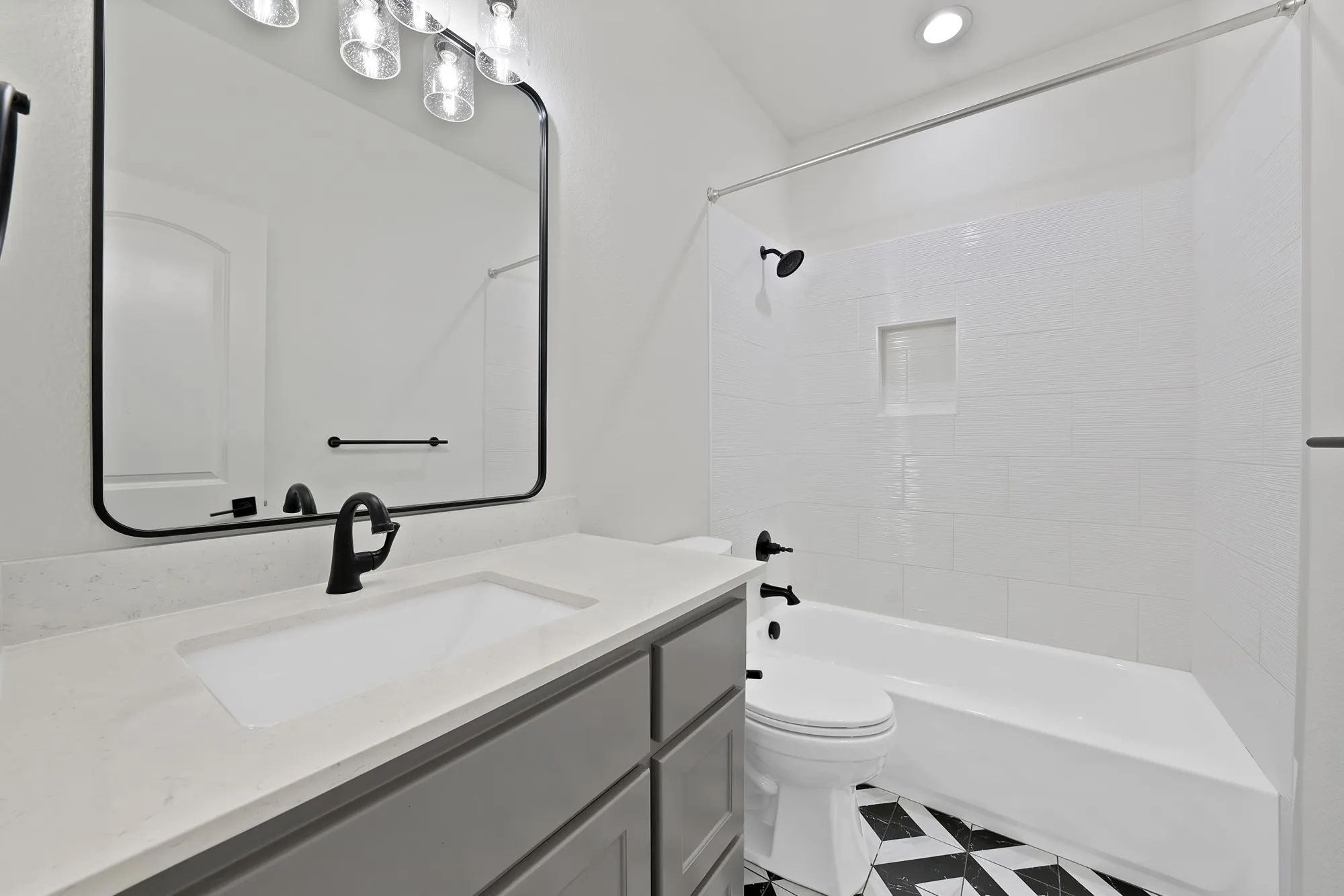 Modern primary bathroom featuring a floating vanity with dual sink configuration, white quartz countertop, matte black hardware accents, and frameless mirror with integrated lighting