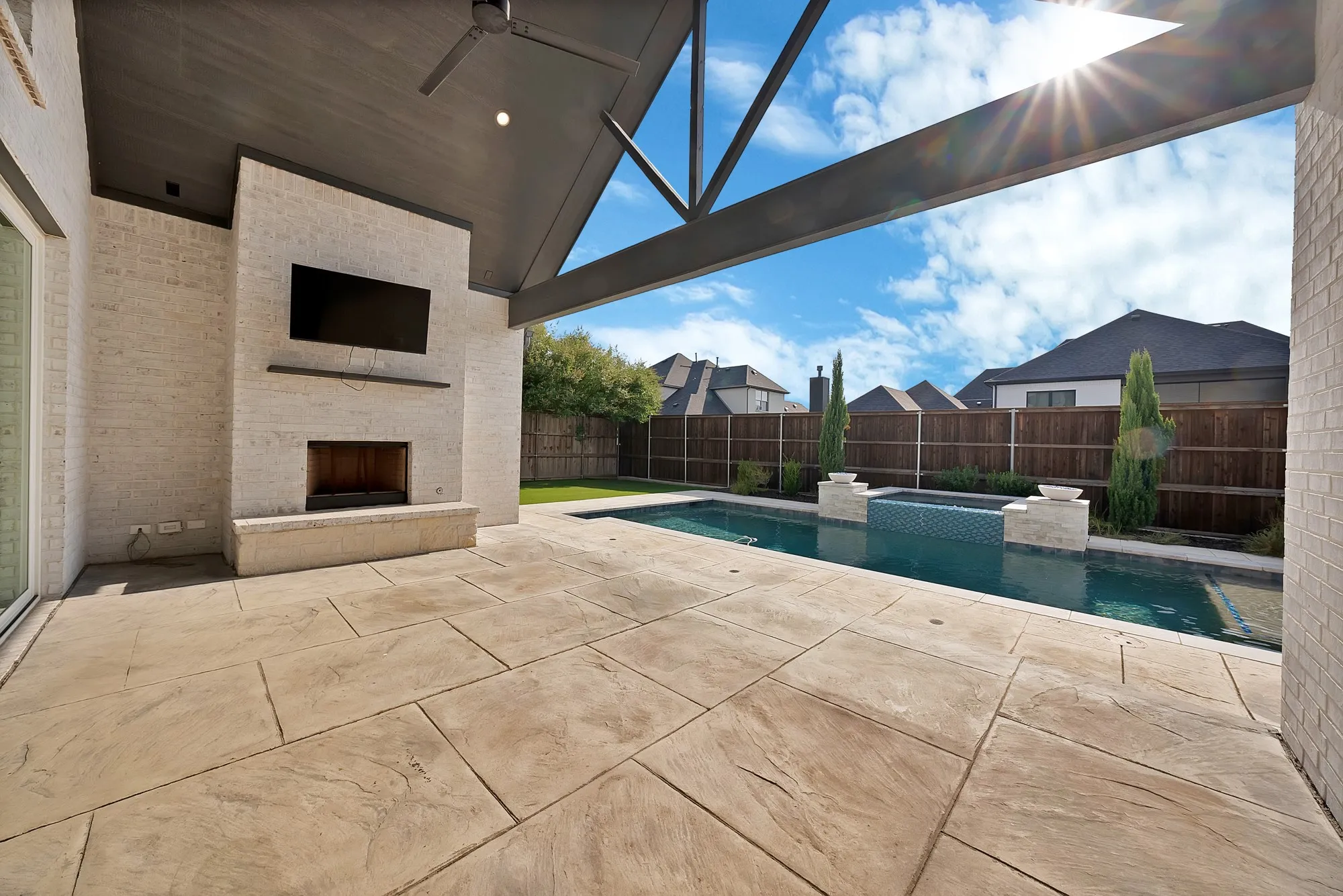 Covered patio featuring a fireplace, a built-in television, and an outdoor fan