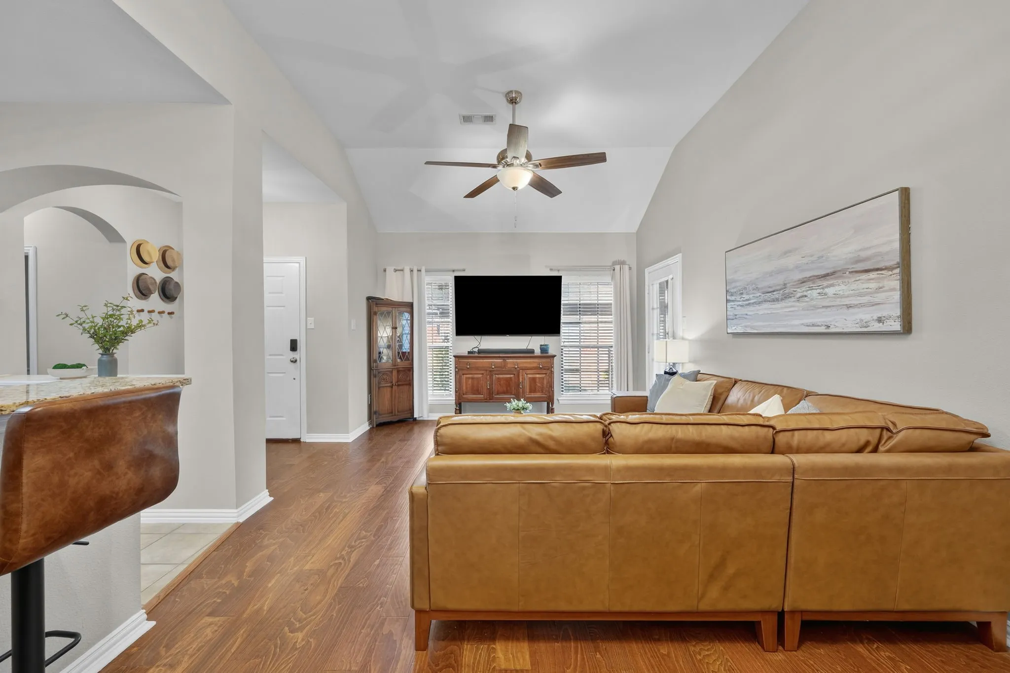 Vaulted ceiling, wood-finish flooring, recessed lighting, ceiling fan, and arched entryway