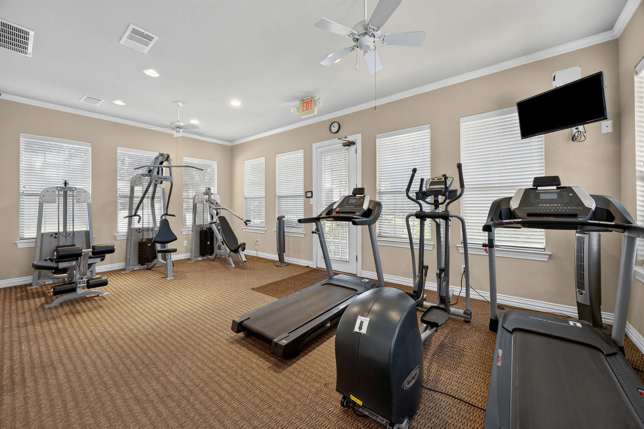 Fitness room with multiple windows, patterned carpet, and recessed lighting