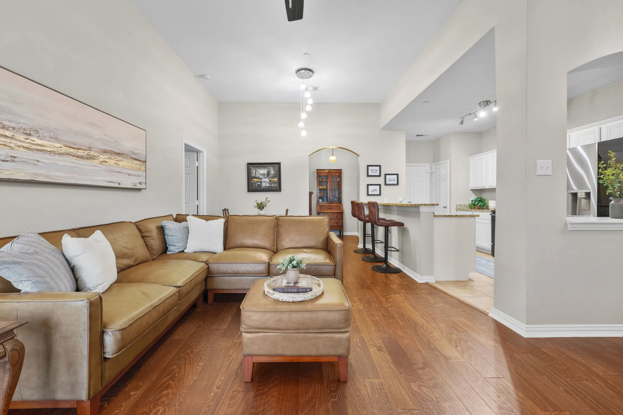 Vaulted ceilings, wood-finish flooring, recessed lighting, arched doorways, and a kitchen pass-through with counter seating