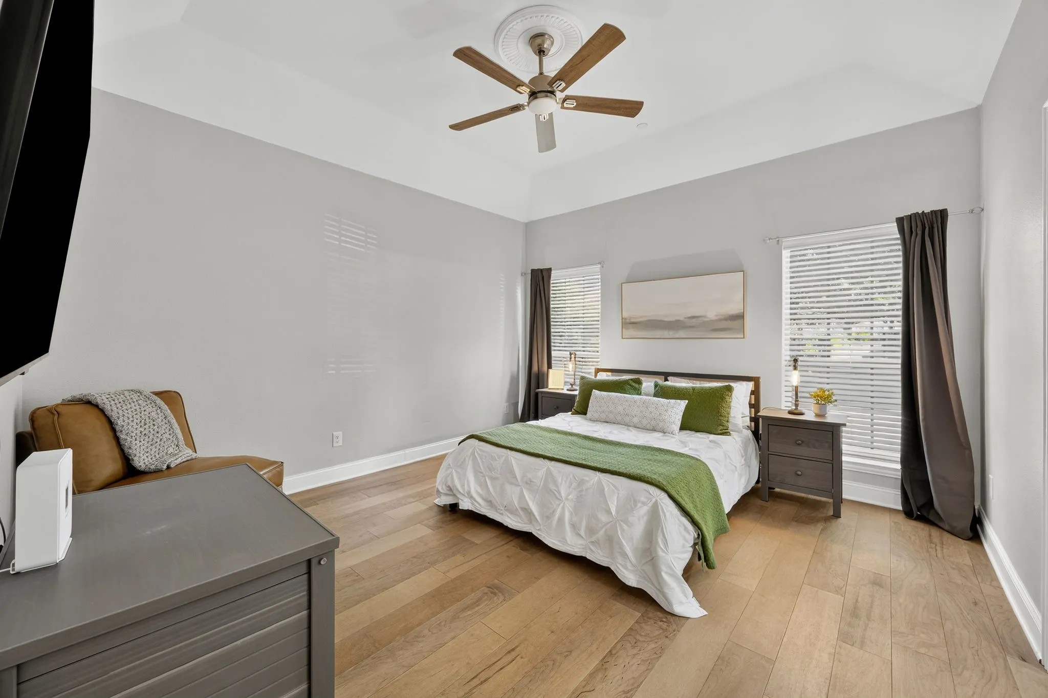 Vaulted ceiling with a ceiling fan, light wood-finish flooring, and multiple windows with blinds