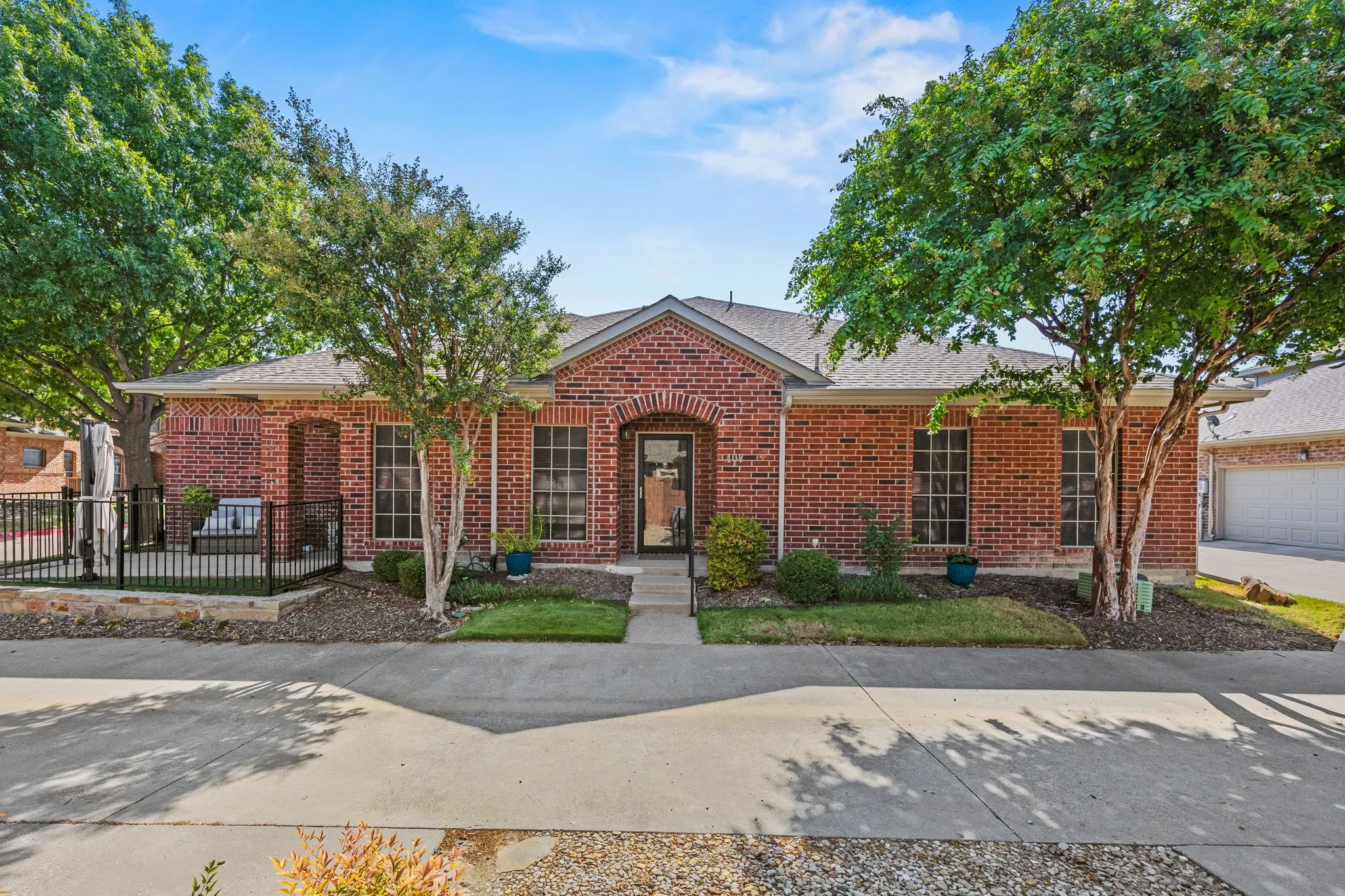 Brick exterior with arched entry, covered front porch, and mature landscaping