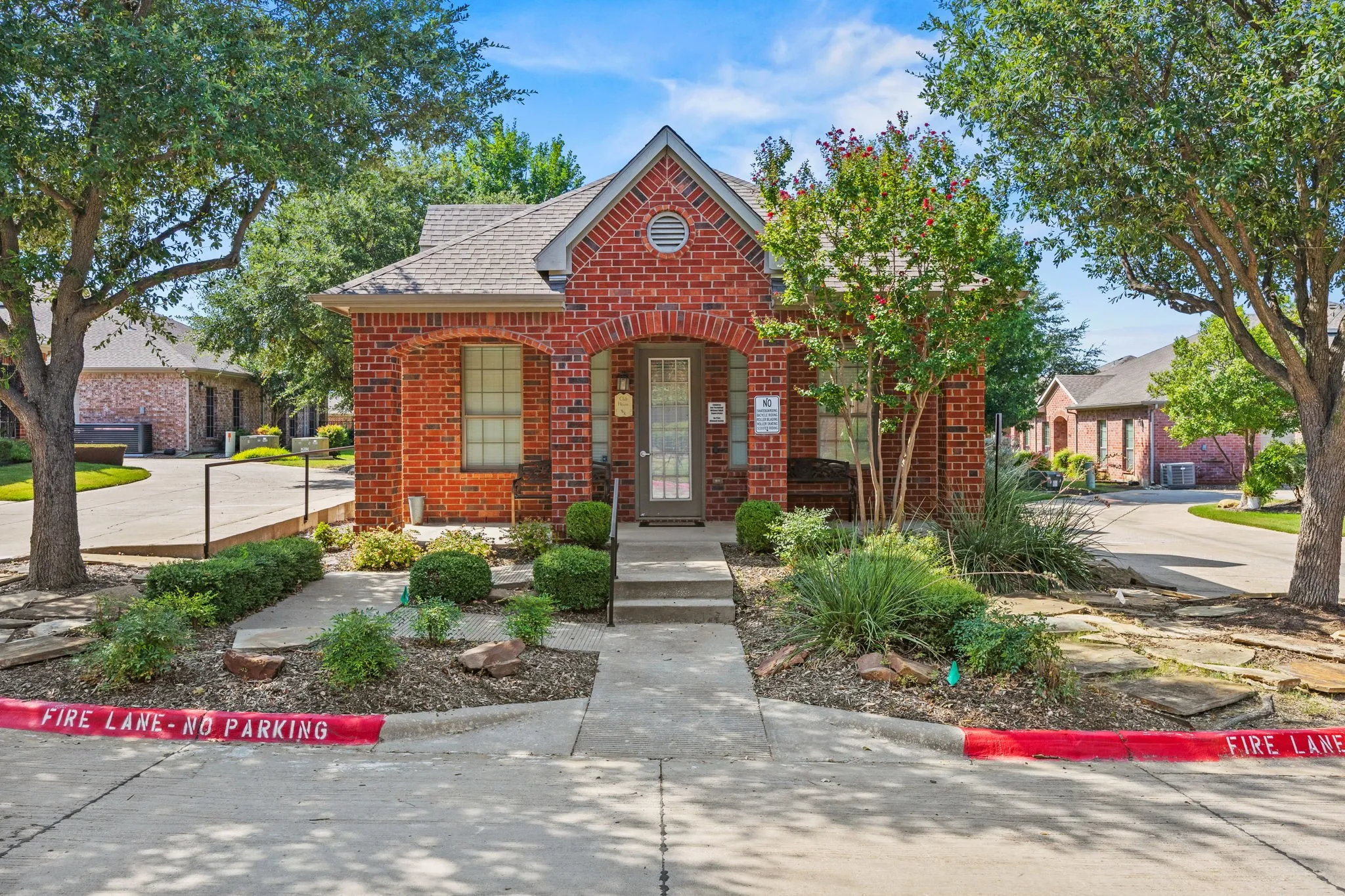 Red brick exterior with arched entry, gabled roofline, and established landscaping