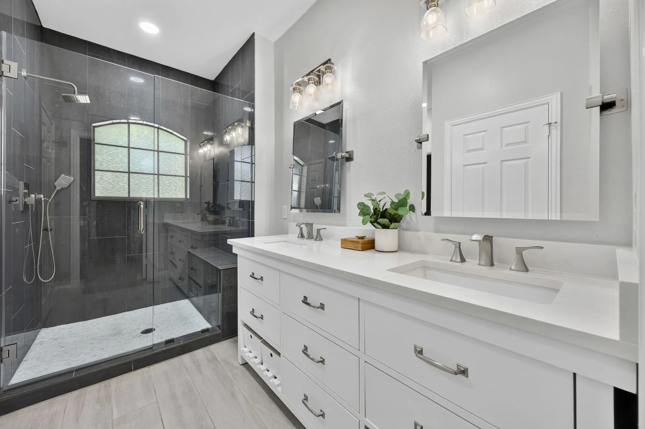 Dual vanity with integrated sinks and white countertops, complemented by contemporary mirrors and light fixtures