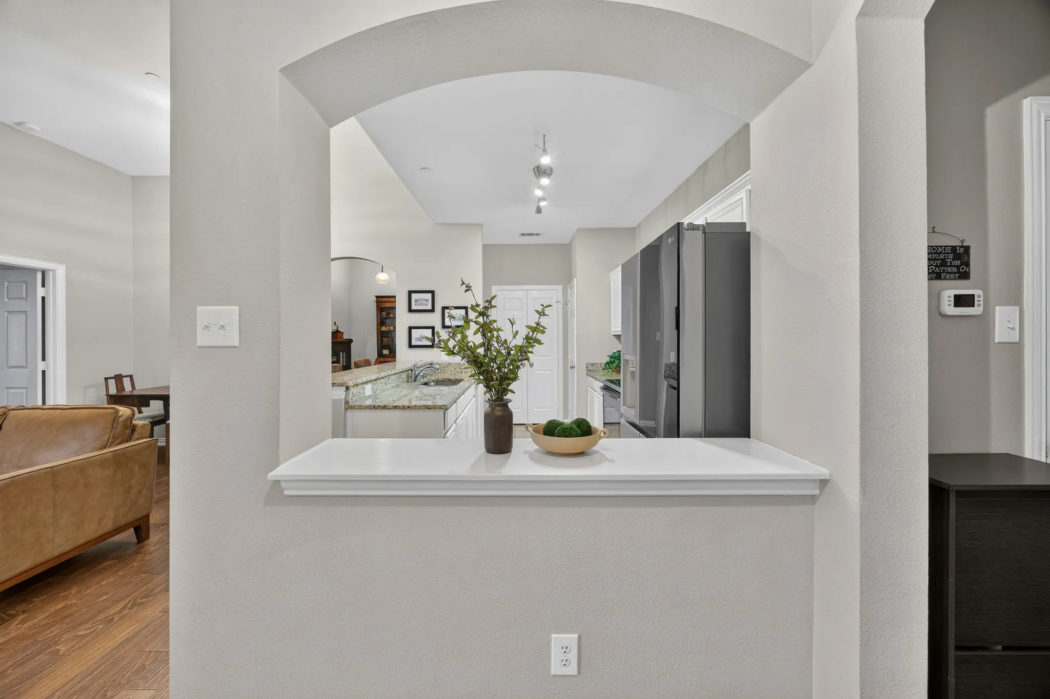Kitchen pass-through with an arched opening, recessed lighting, and a white ledge
