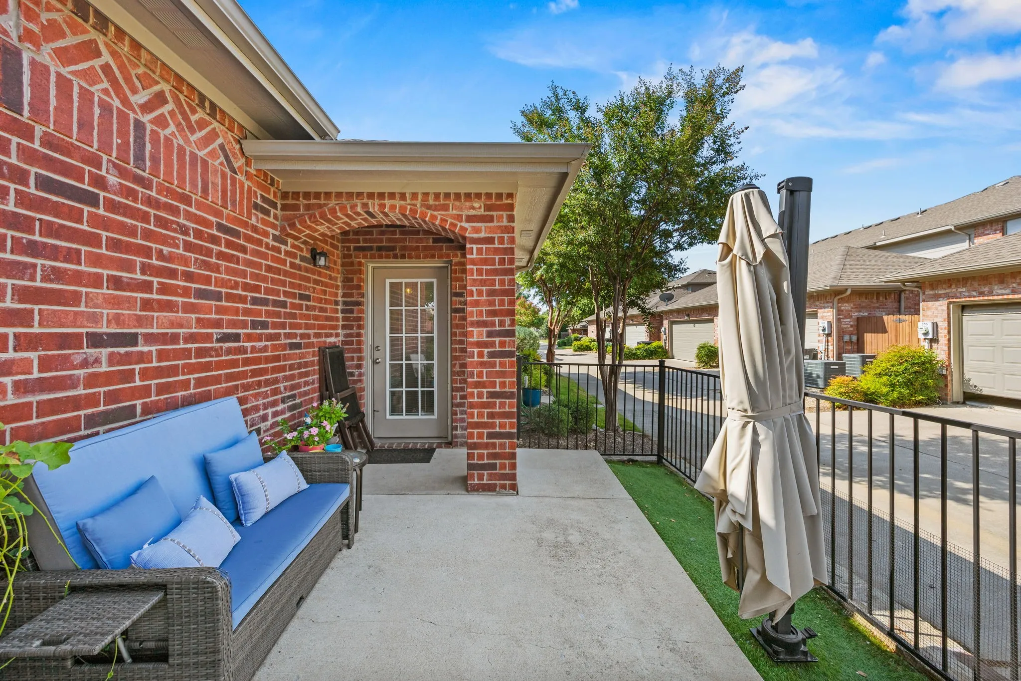 Brick exterior with arched entryway, concrete patio, and fenced perimeter