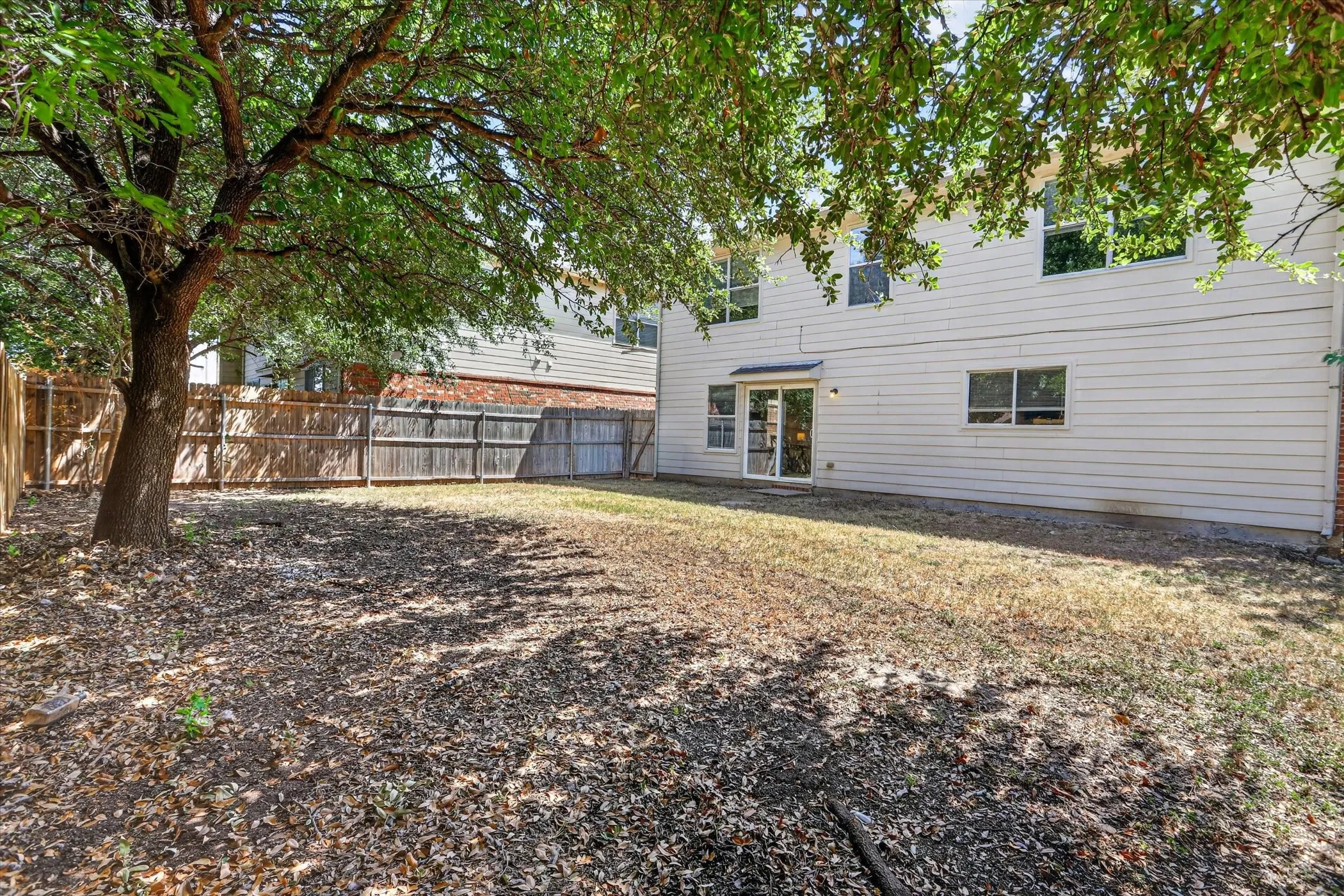 Expansive backyard with a full privacy fence and mature shade trees