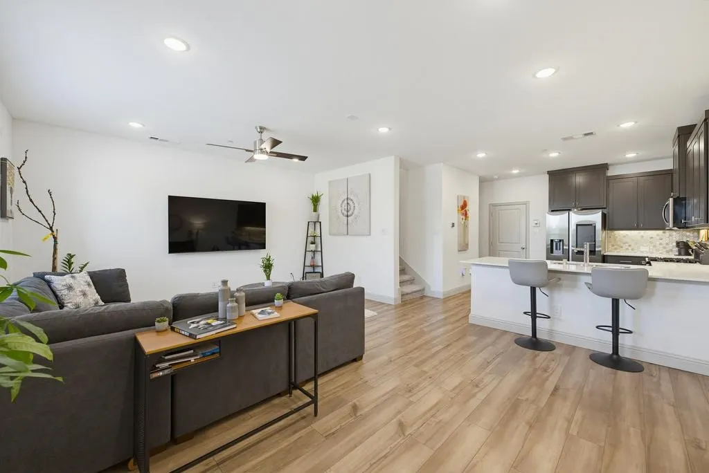 Recessed lighting, wood-finish flooring, kitchen island with seating, stainless steel appliances, and dark-finish cabinetry