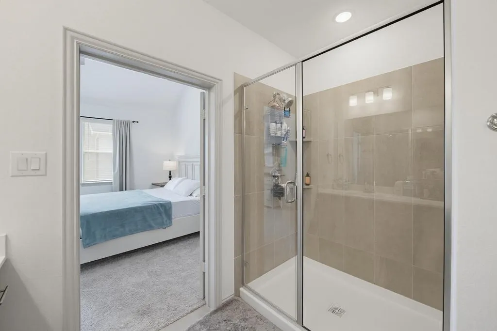 Glass-enclosed shower with tile surround and integrated shelving