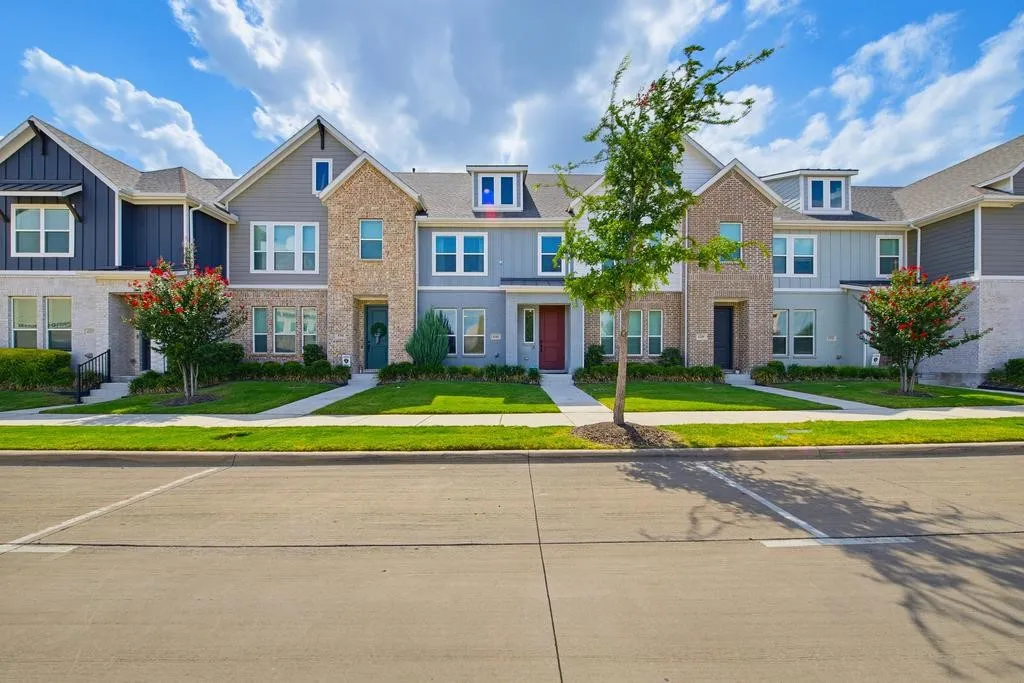 Contemporary townhomes featuring brick and siding exteriors, dormer windows, and a manicured lawn