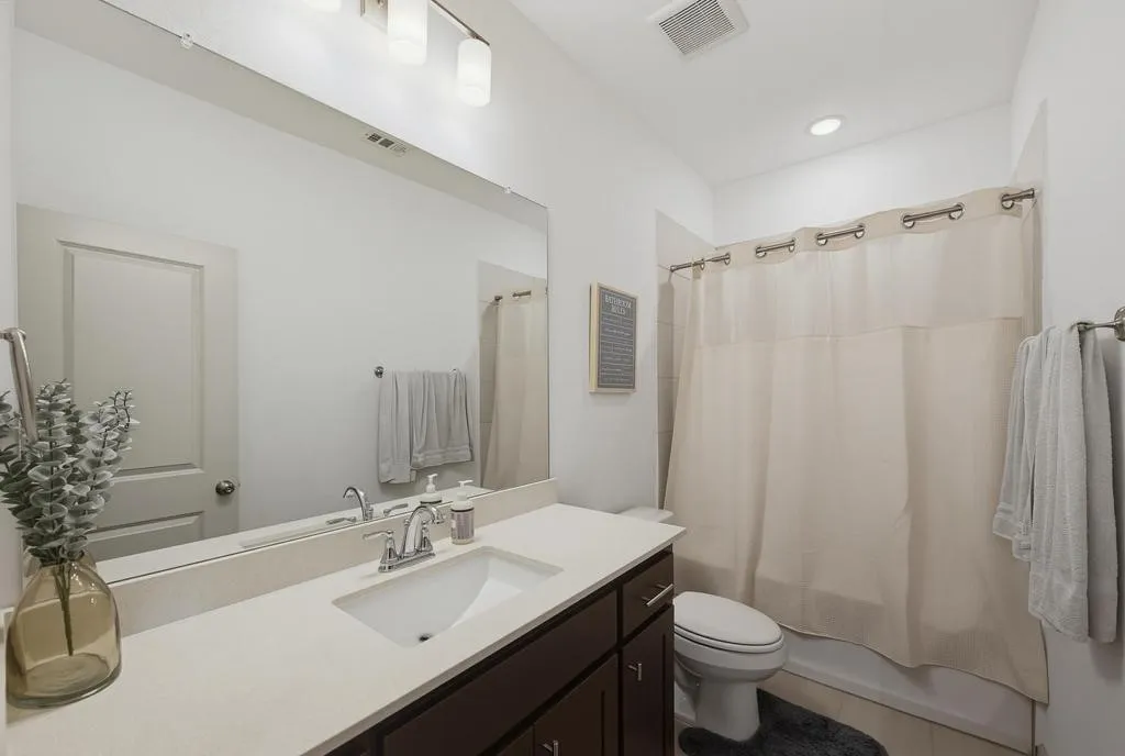 Vanity with integrated sink, chrome faucet, and expansive wall-mounted mirror
