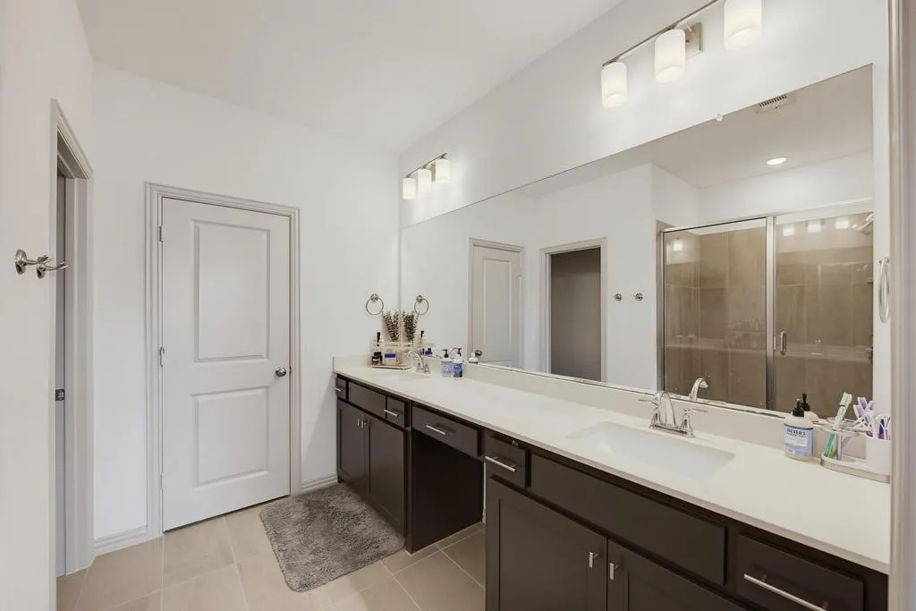 Dual vanity with white countertop, dark wood-finish cabinetry, and contemporary lighting fixtures