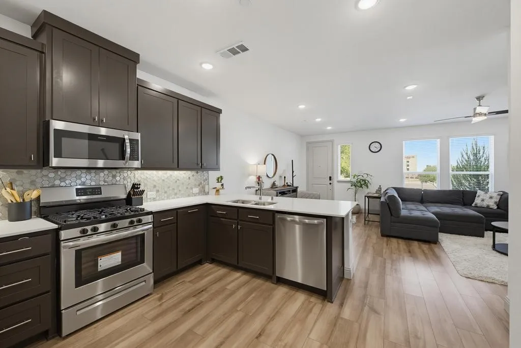 Kitchen featuring dark wood cabinetry, stainless steel appliances, white countertops, and a patterned tile backsplash