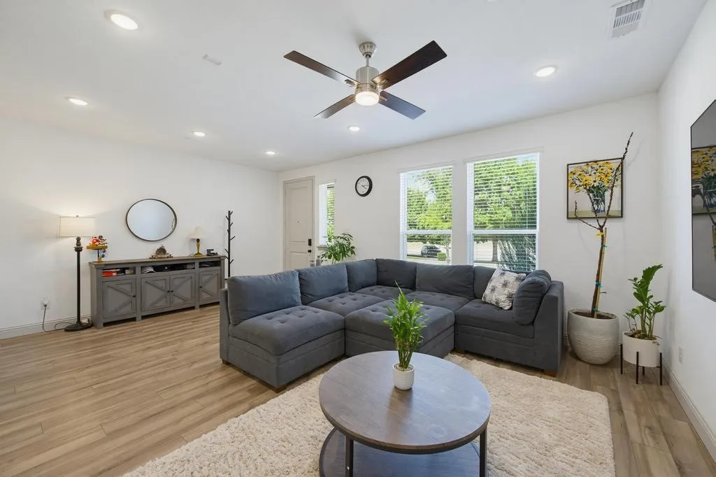 Open-concept living area with wood-finish flooring, recessed lighting, and a ceiling fan