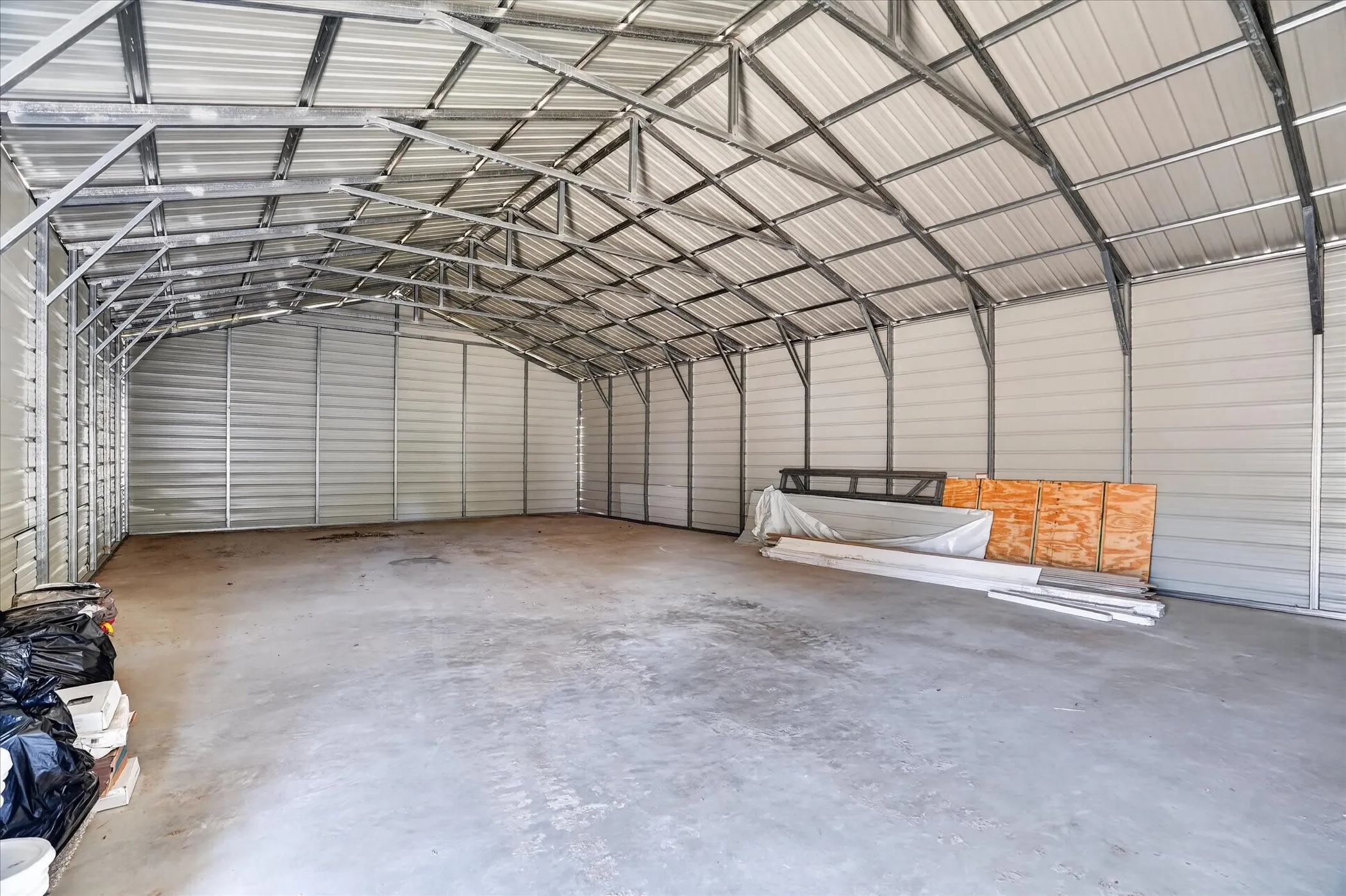 Expansive open structure featuring a concrete floor, high vaulted ceiling, and metal wall panels