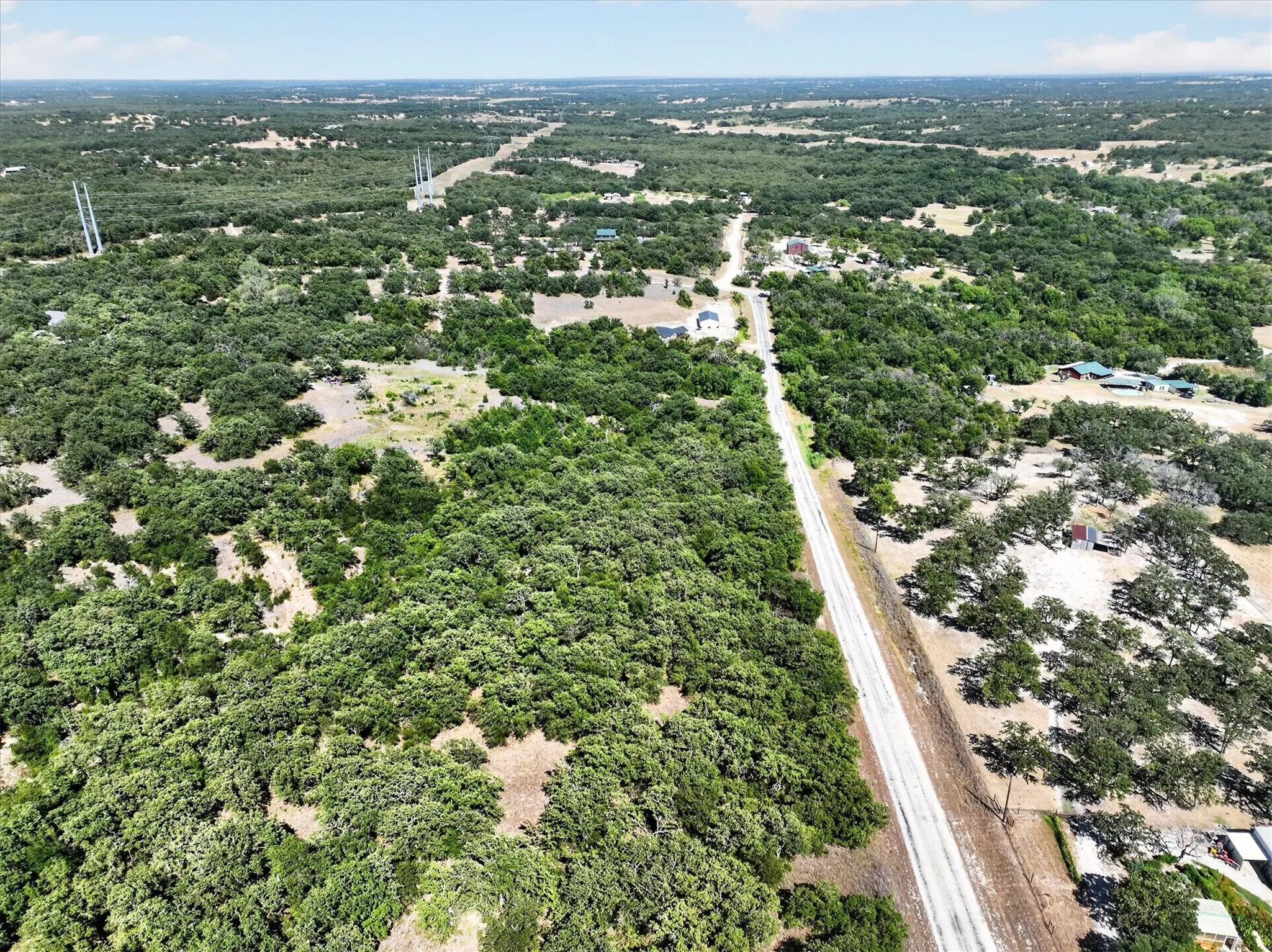 Expansive treed landscape with scattered cleared areas and a visible roadway