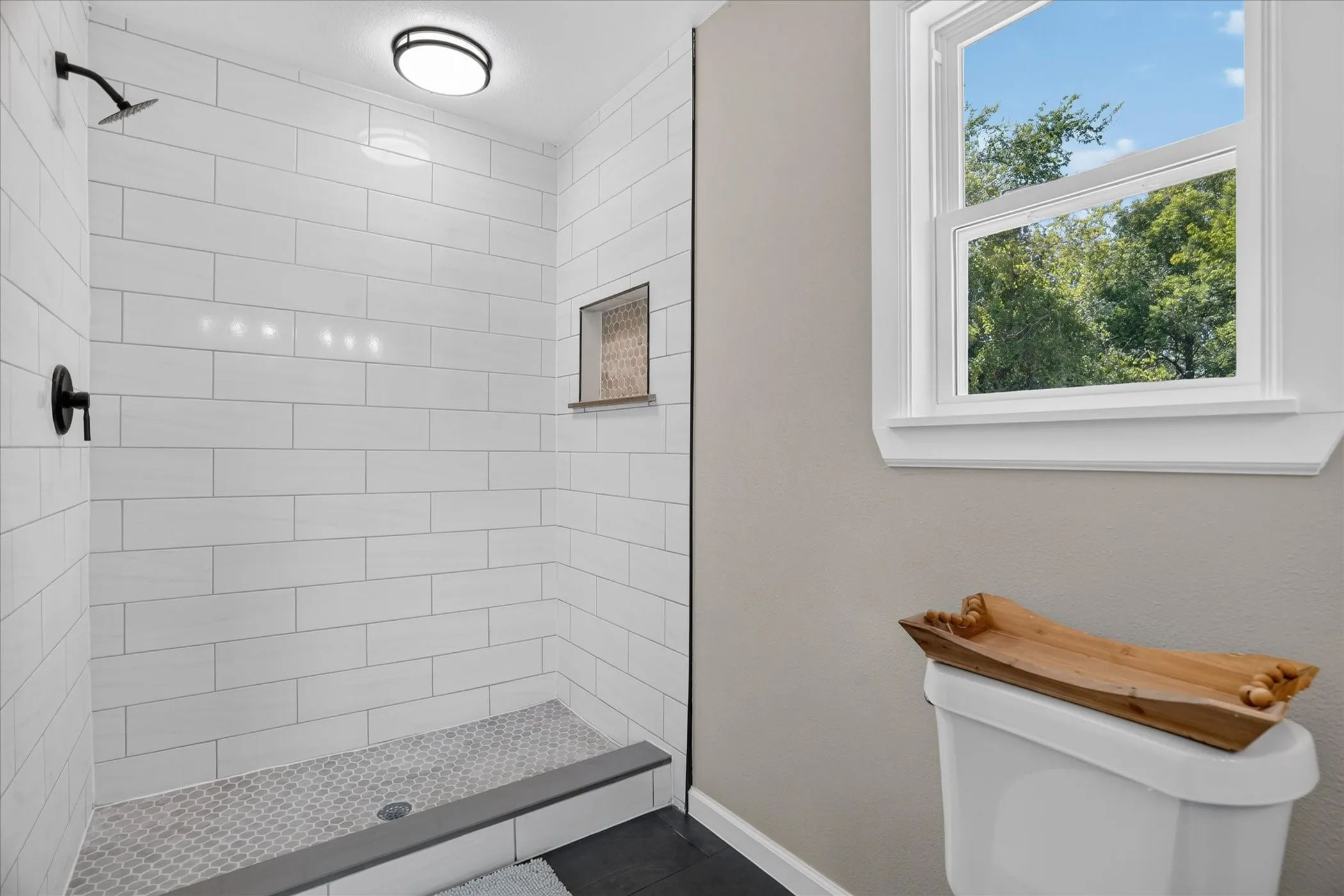 Walk-in shower featuring white subway tile, a recessed niche, black fixtures, and a hex tile floor