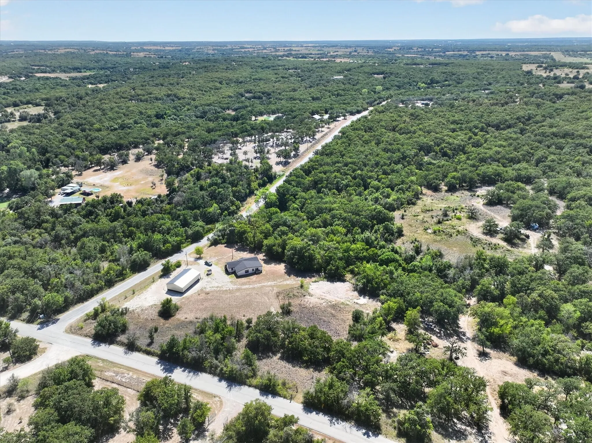 Expansive wooded acreage featuring a single-story dwelling and a large outbuilding