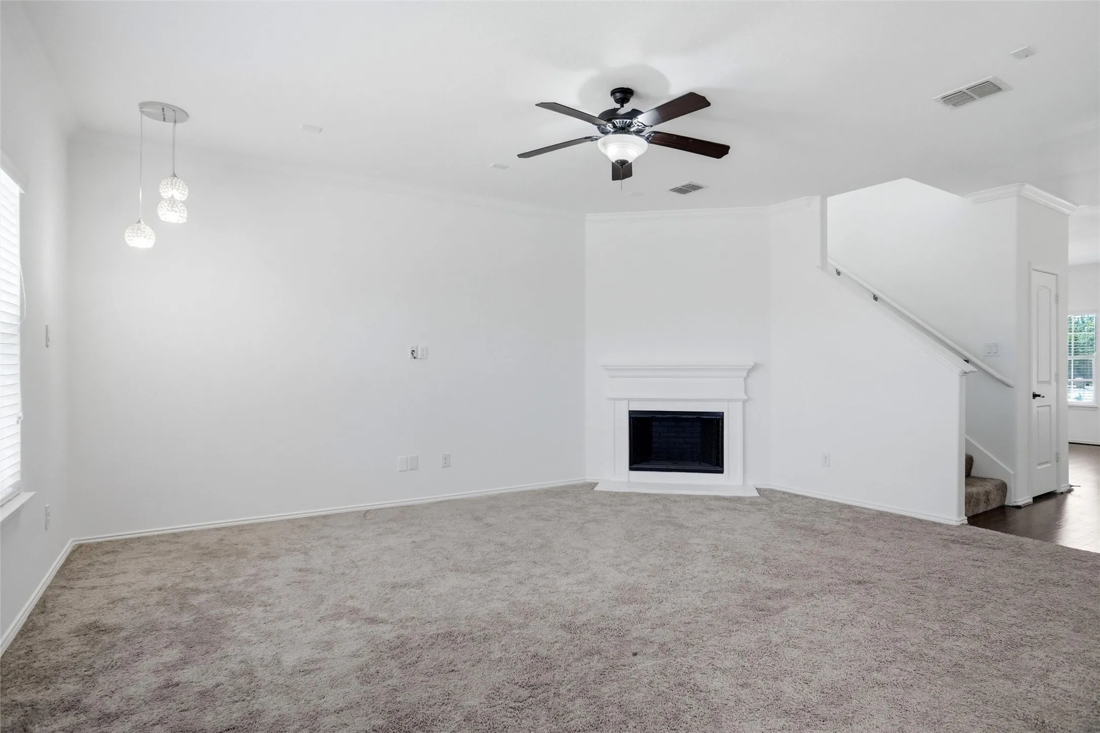 Spacious living area featuring a built-in fireplace, ceiling fan, recessed lighting, and carpet flooring